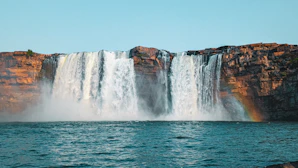 A waterfall with a rainbow in the middle of it