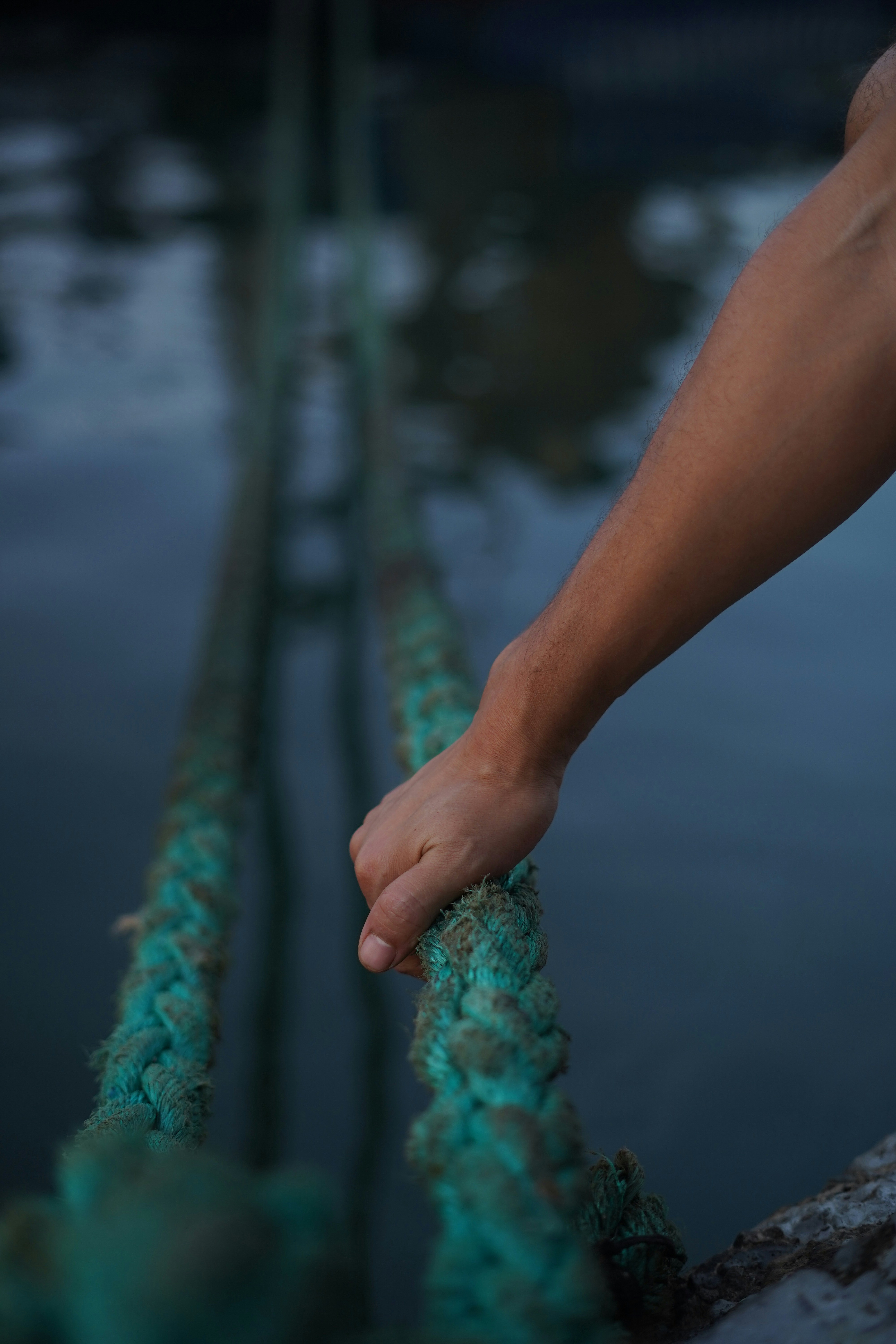 A person's hand on a rope near a body of water