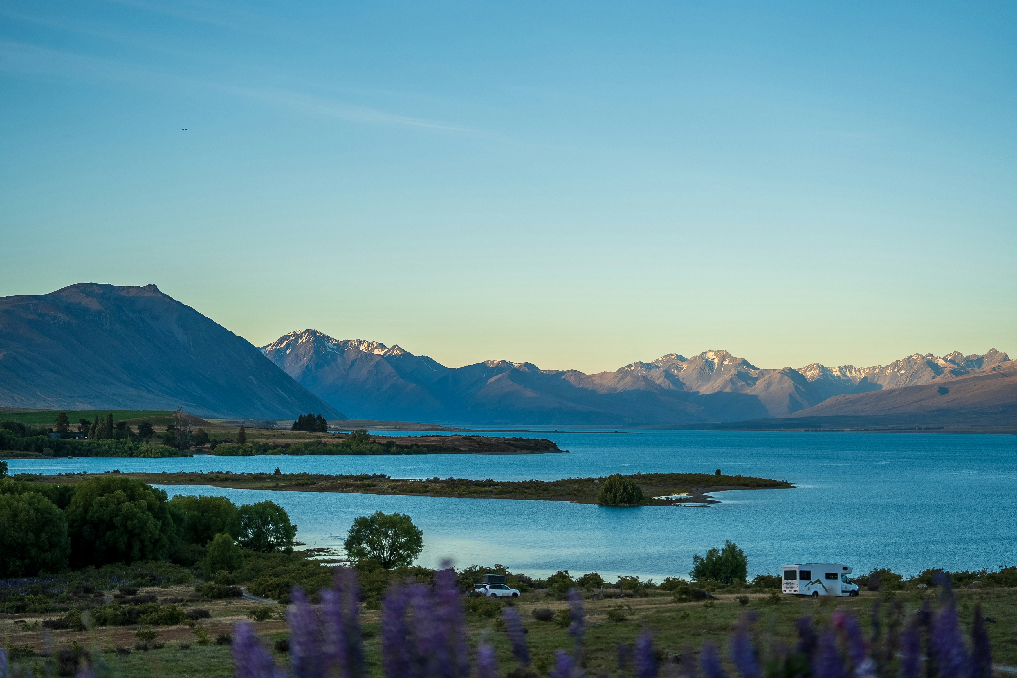 Ein See, umgeben von lila Blumen und Bergen