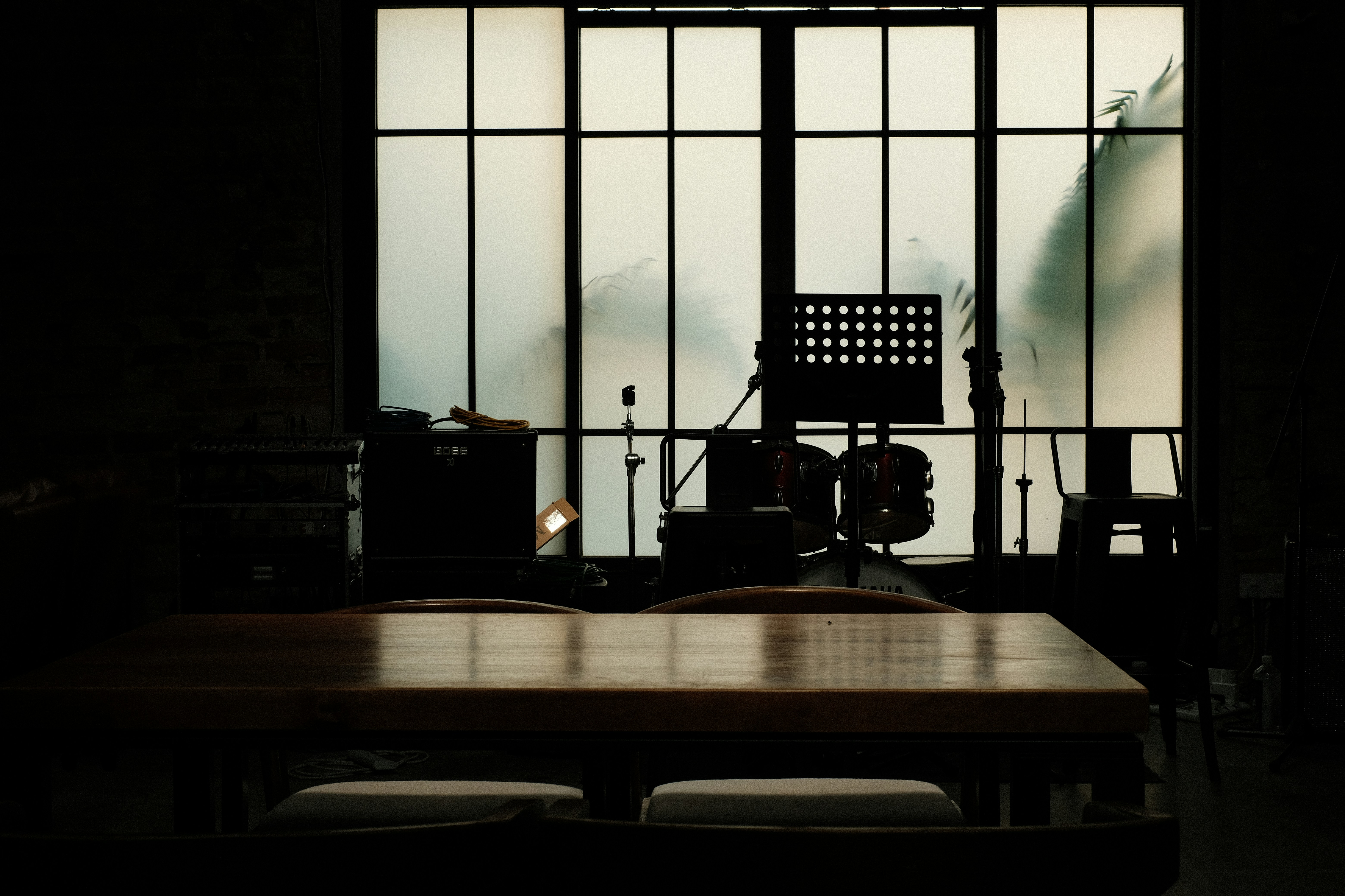 A room with a table, drums, and a large window
