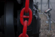 A close up of a red chain attached to a black object