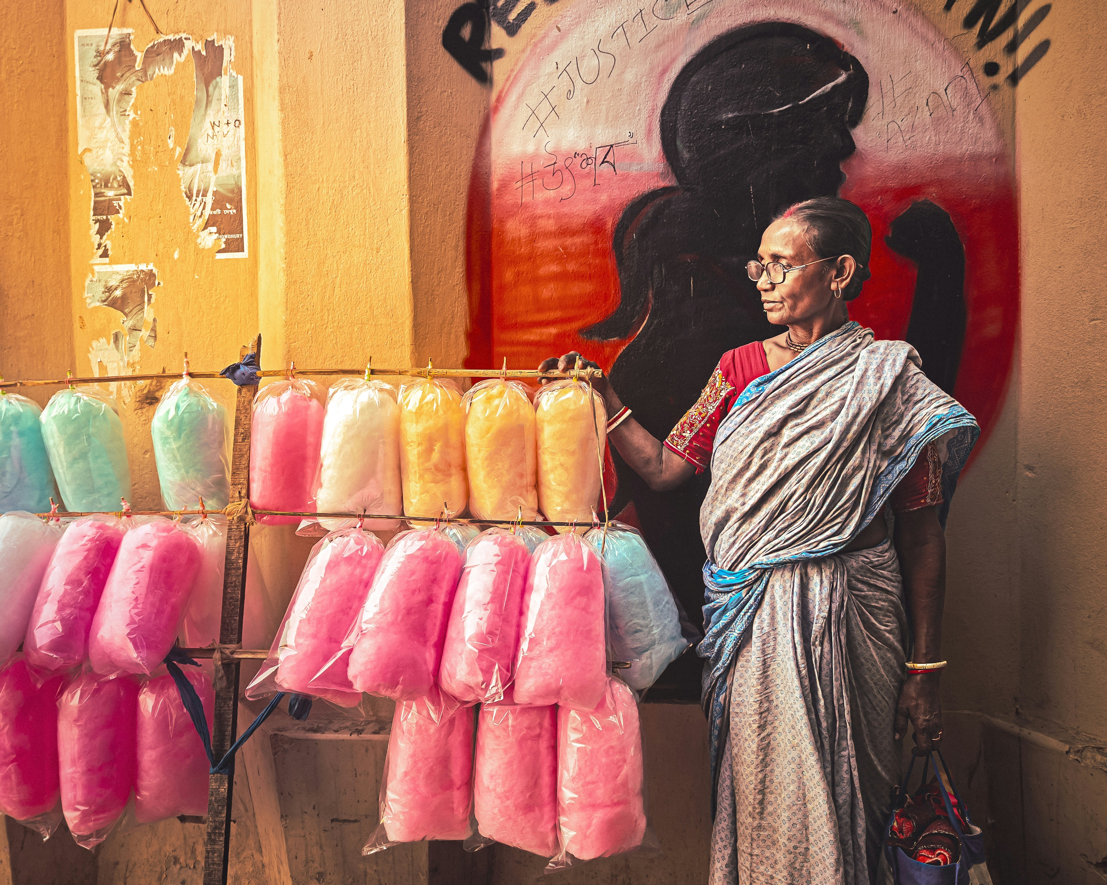 A woman standing in front of a display of dyed cotton candy