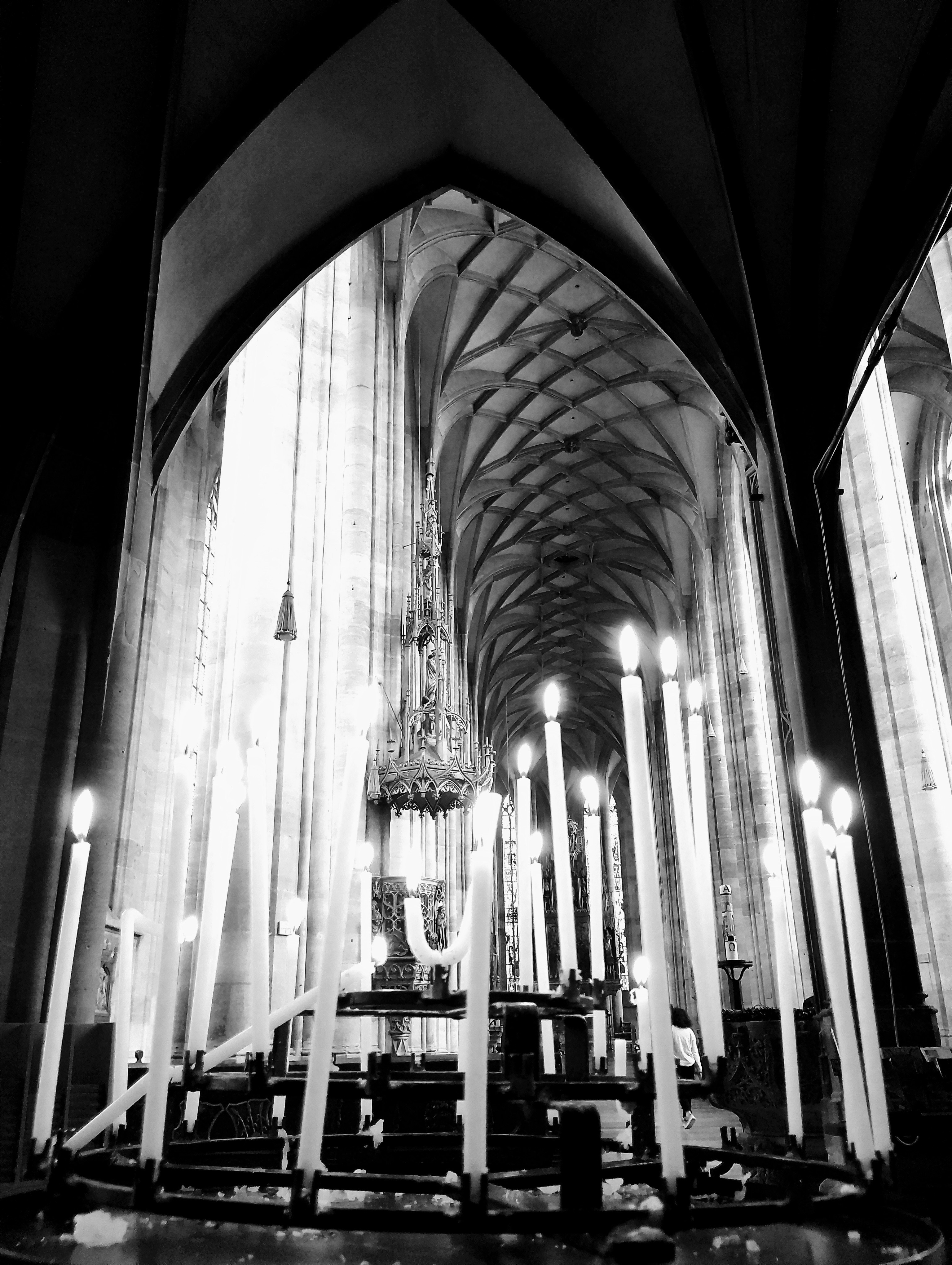 Grand cathedral interior with soaring vaulted ceilings, candlelight flickering on ancient stone and stained glass windows