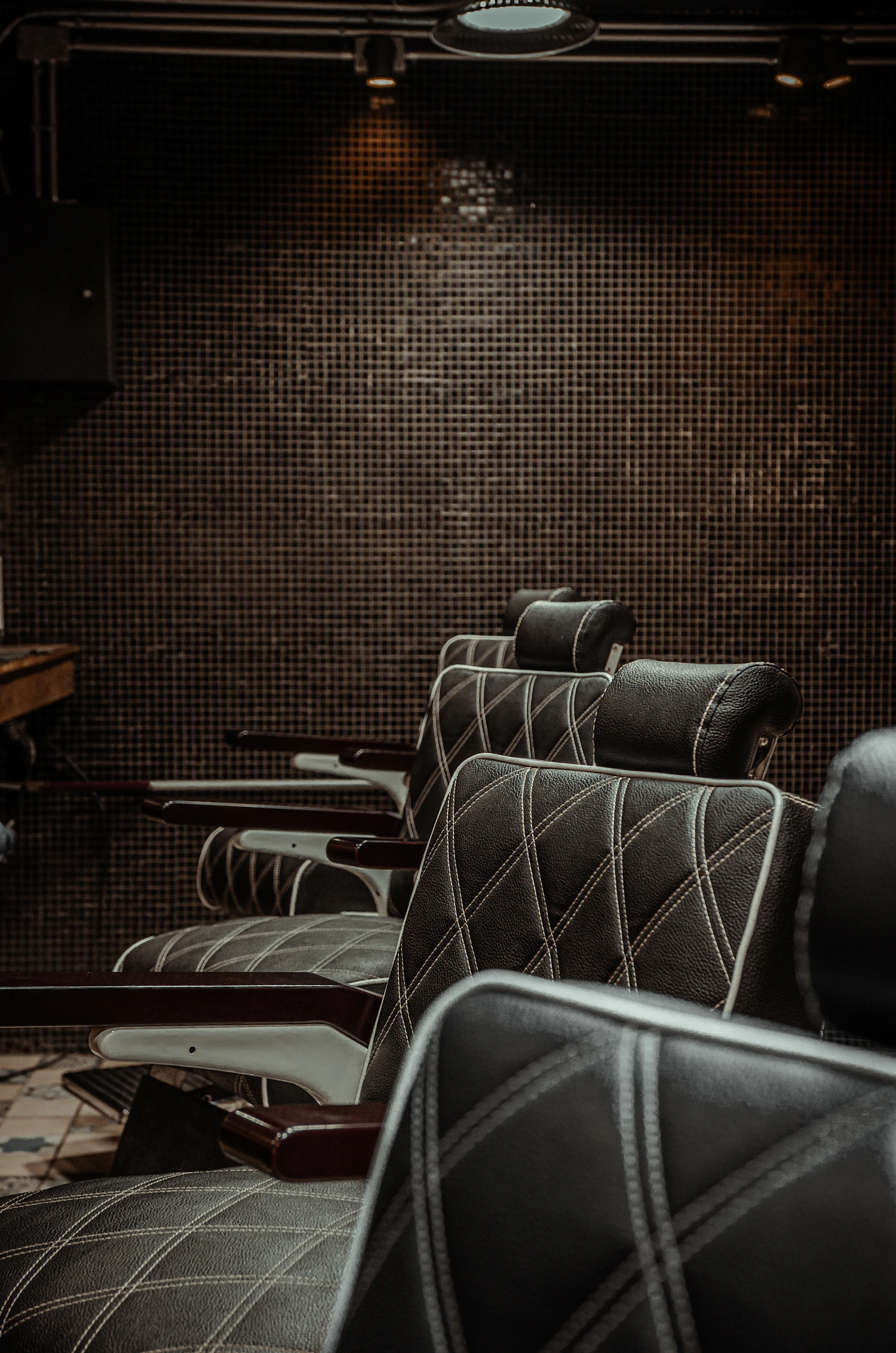 A line of empty chairs down a dark room, chrome arms catching the last of the light