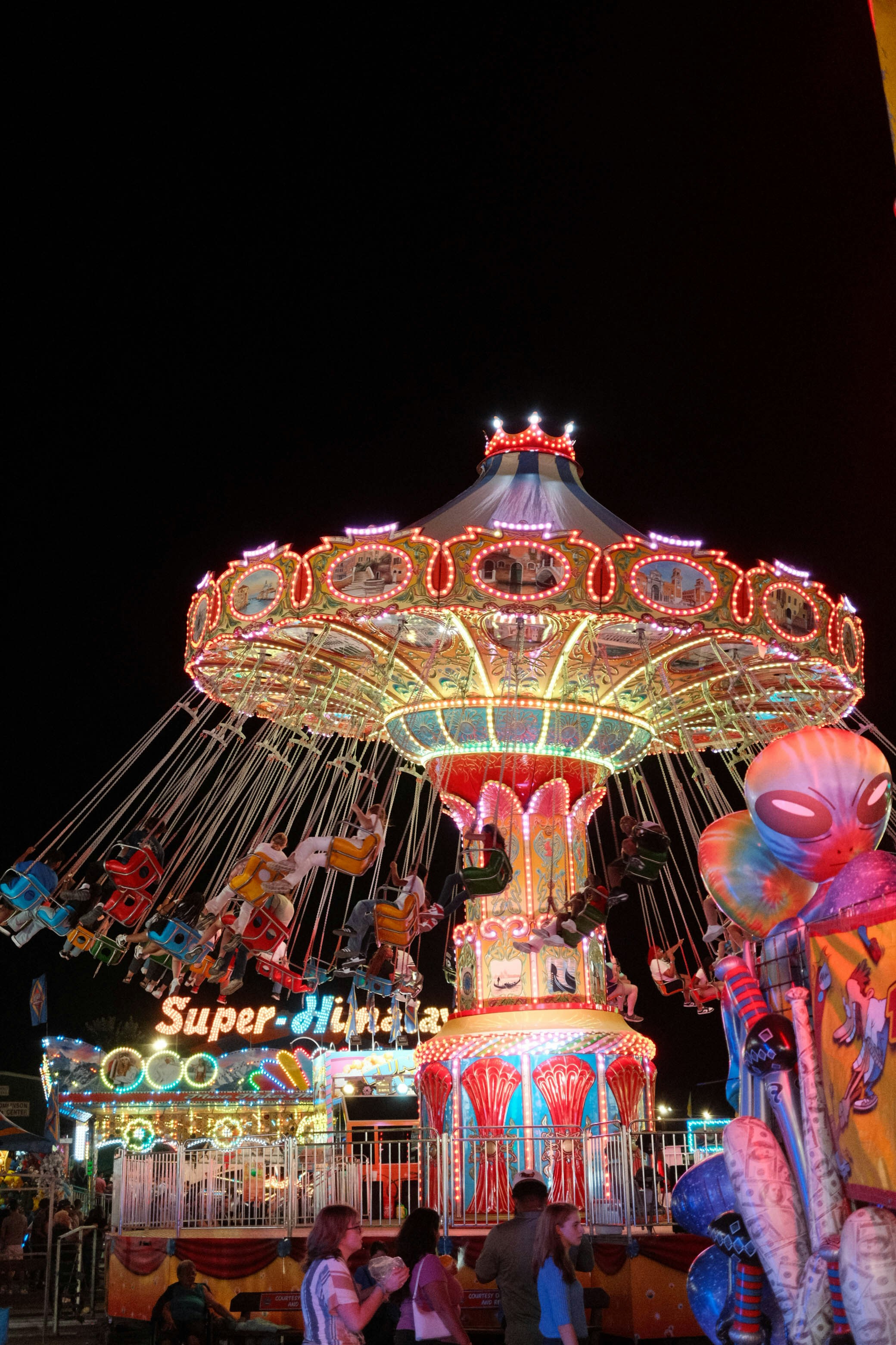 A merry go round at night with people walking around