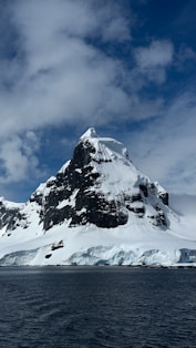 A large mountain covered in snow next to a body of water