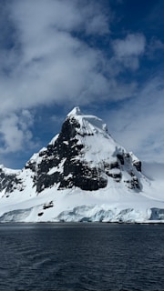 A large mountain covered in snow next to a body of water