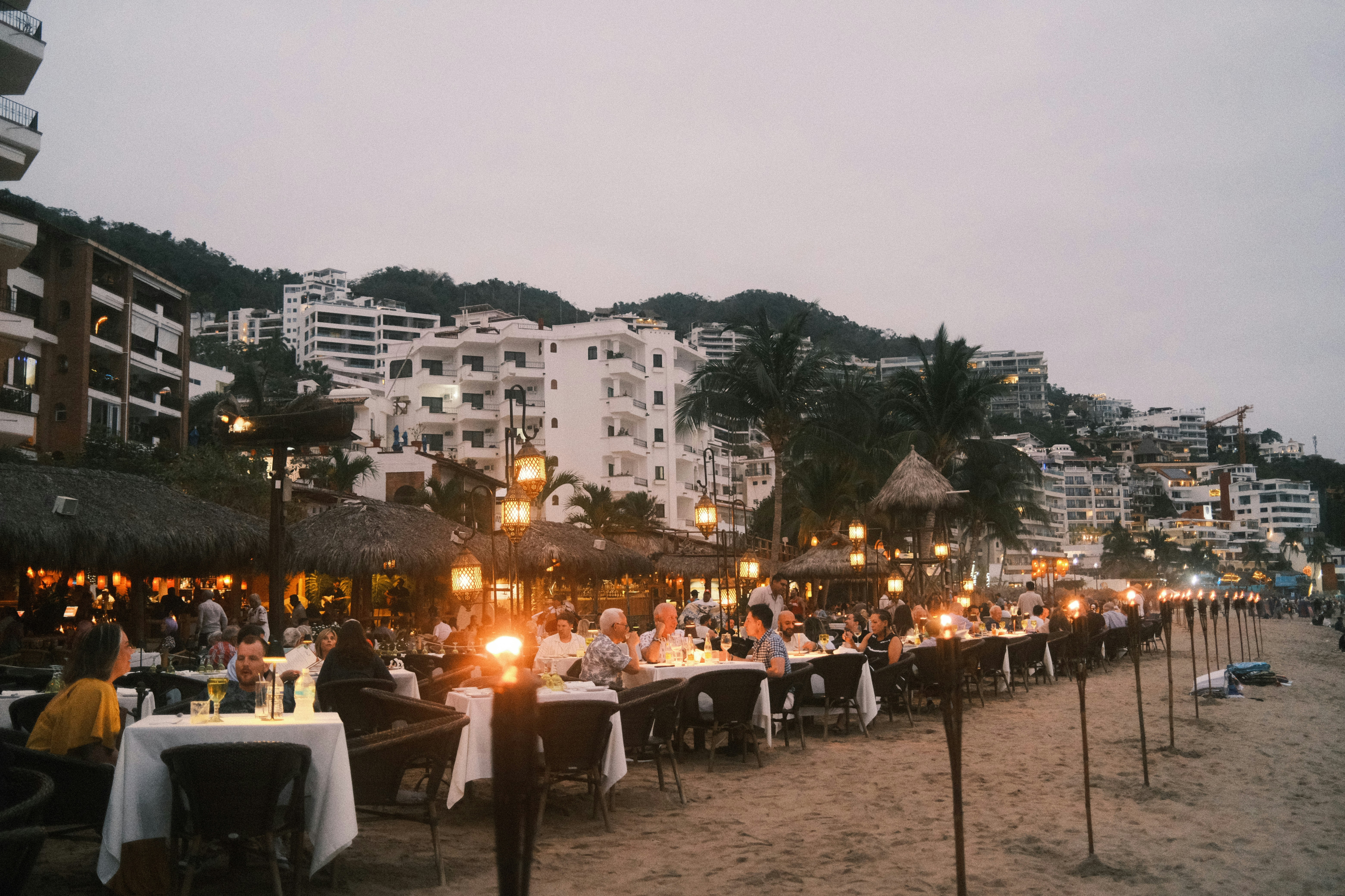 A group of people sitting at tables on a beach