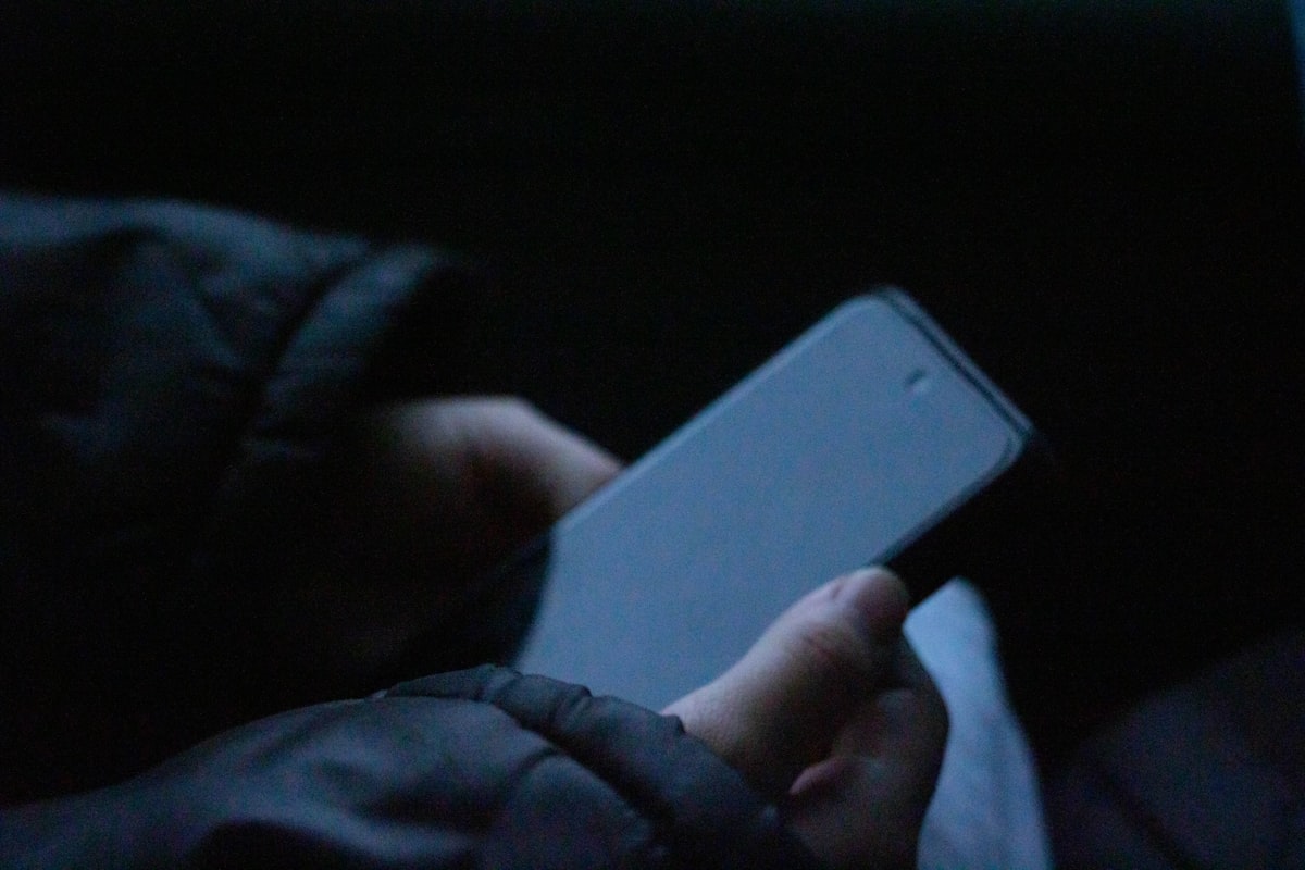 Smartphone allumé dans le noir à côté d'un lit