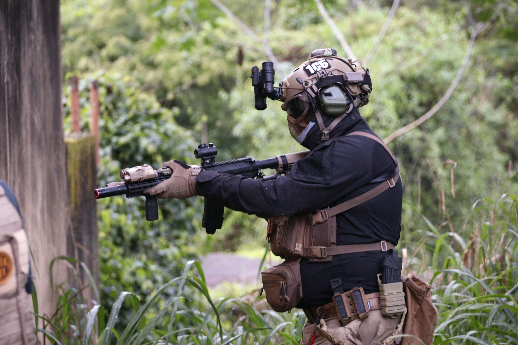 A man in a paintball uniform aiming a gun