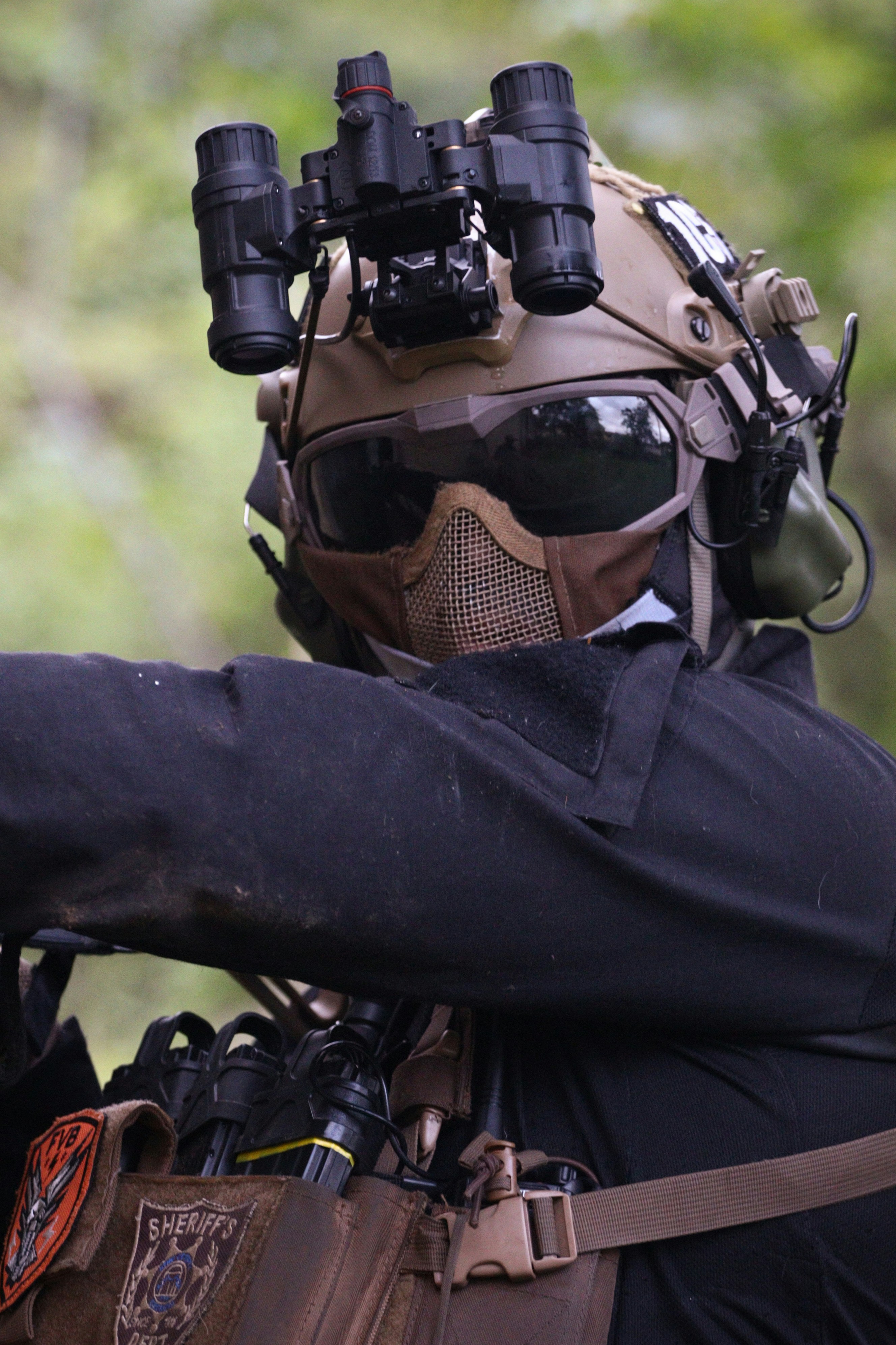 A man wearing a helmet and goggles holding a gun