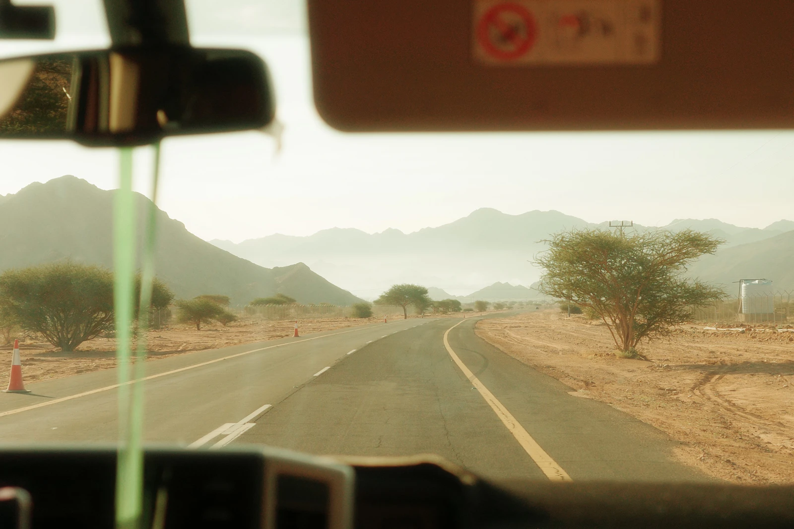 A paved road seen through a windscreen in the Saudi desert