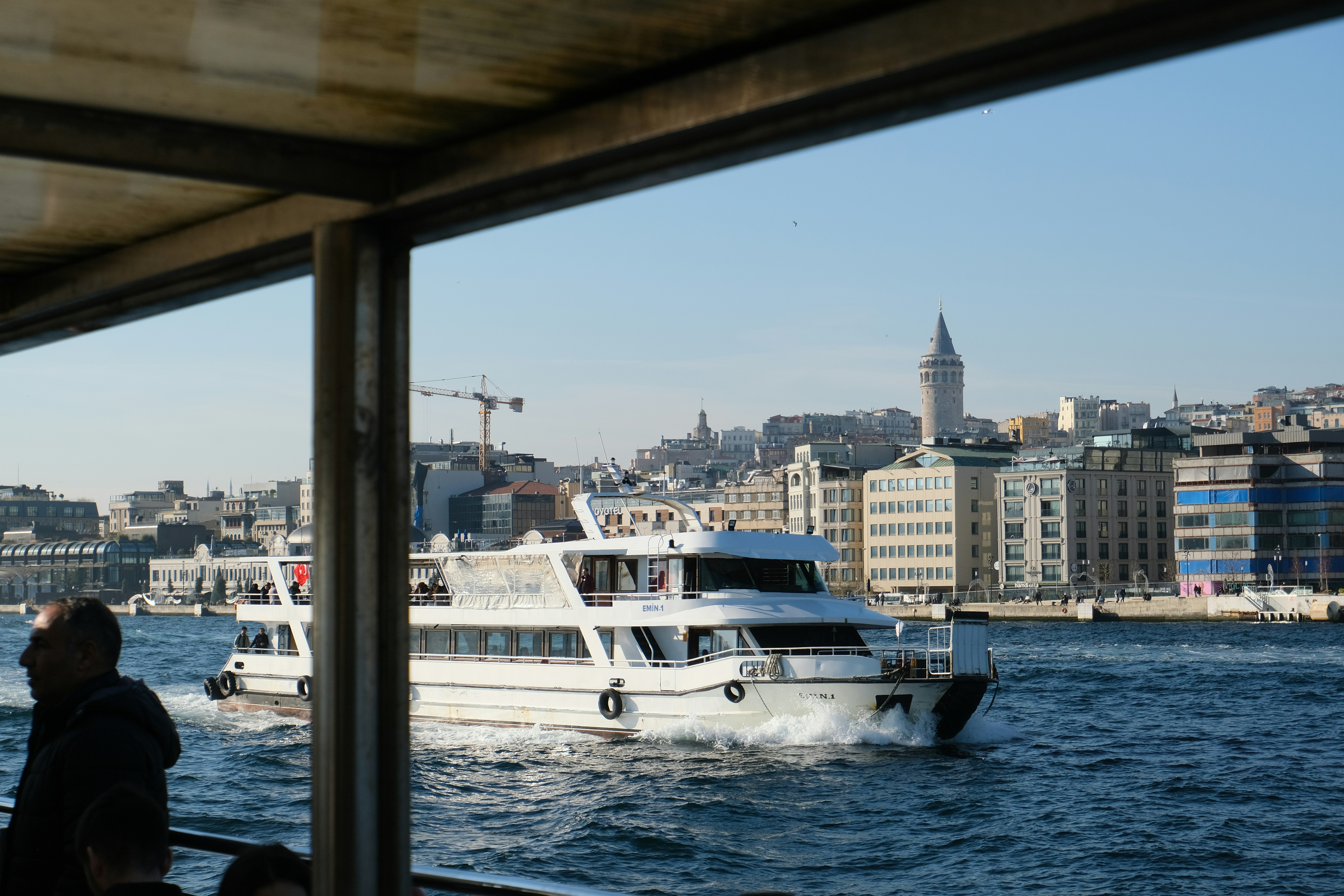 A boat traveling down a river next to a city. Стамбул