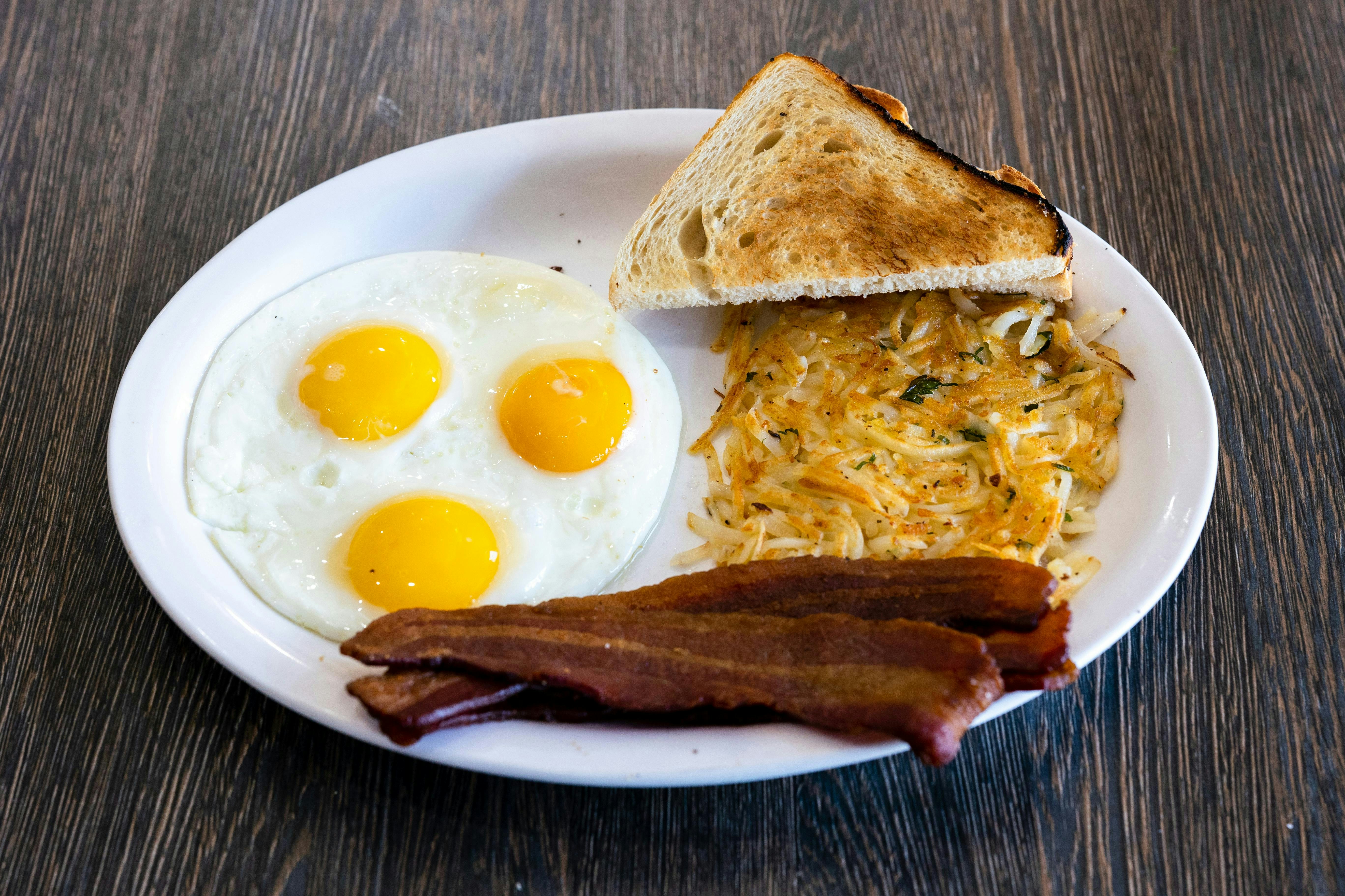 Full country breakfast plate with sunny side up eggs, crispy bacon, toast, and golden hash browns