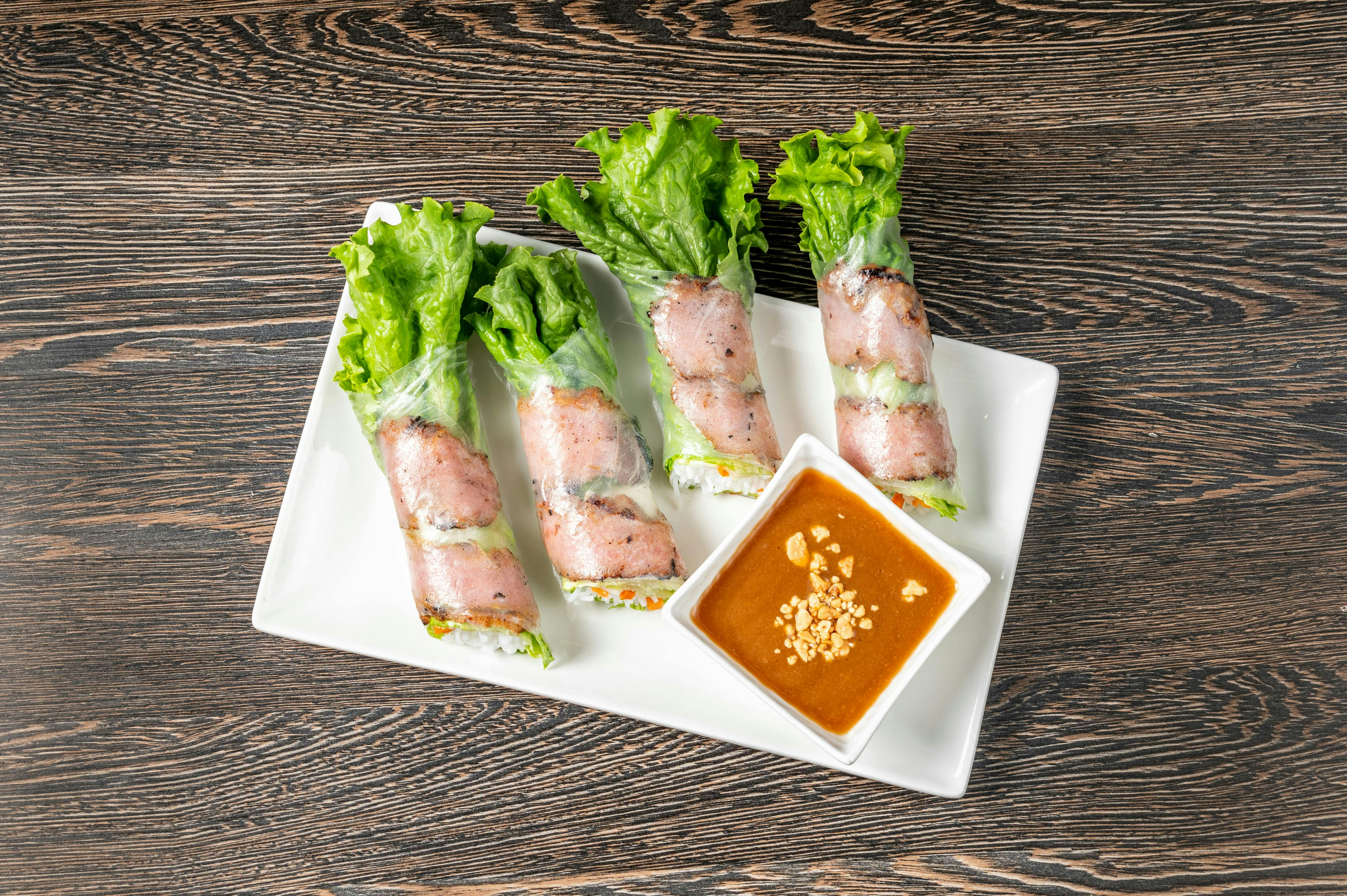 A white plate topped with lettuce wrapped in meat