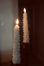 Two white candles sitting on top of a table