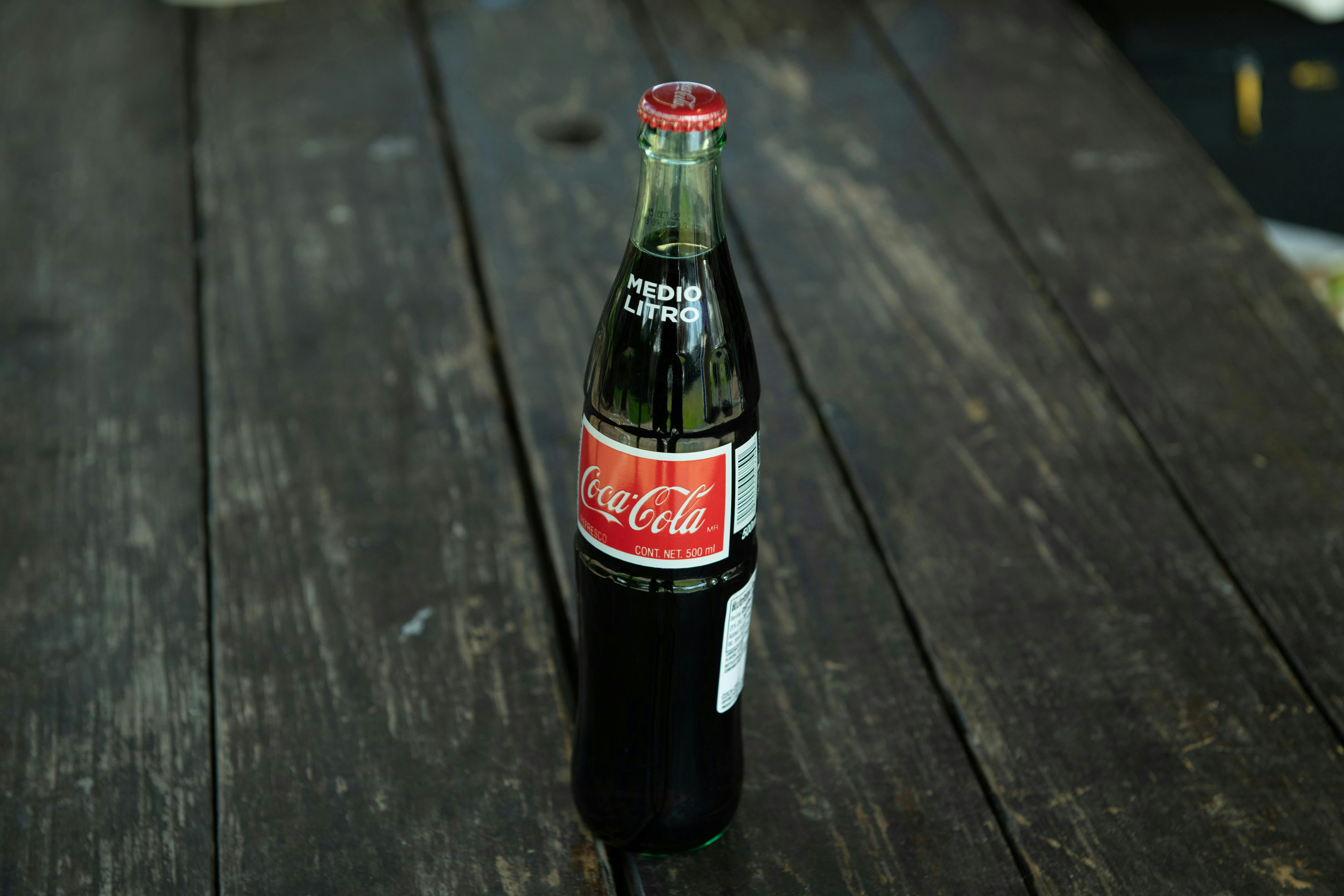 A bottle of coca cola sitting on top of a wooden table