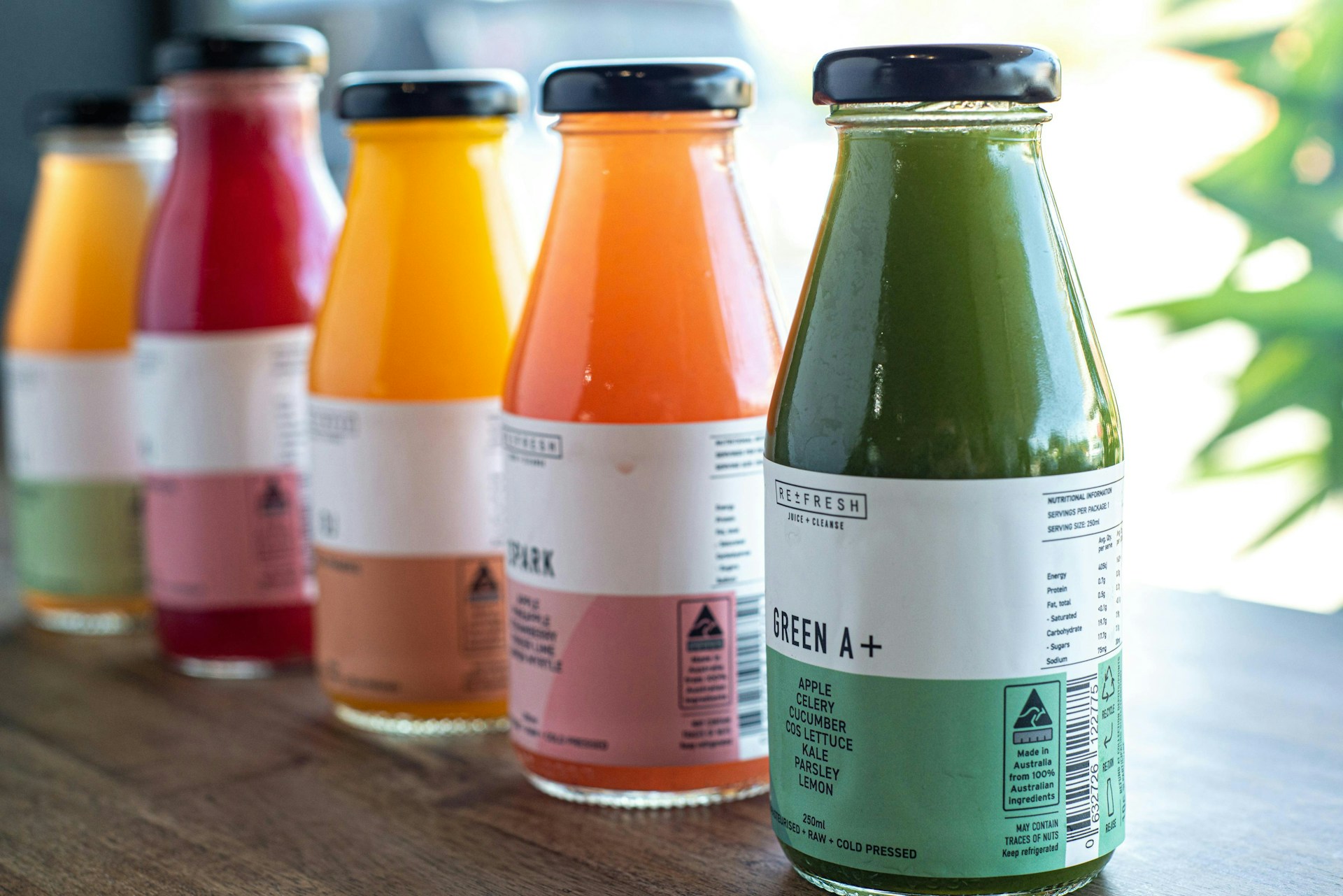 A row of bottles of juice sitting on top of a wooden table