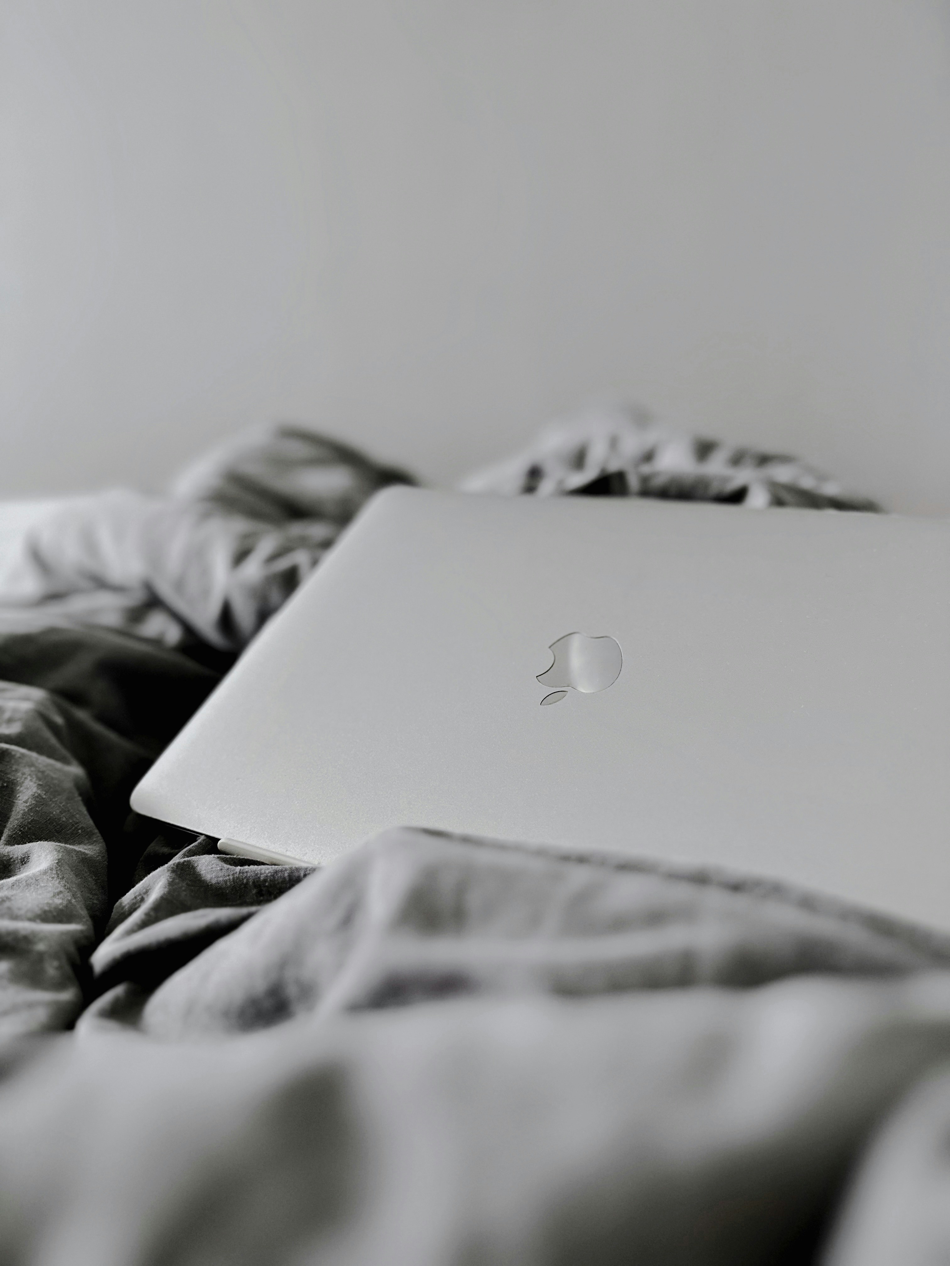 A white apple laptop sitting on a bed