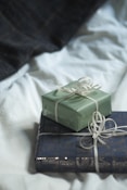 Two wrapped presents sitting on top of each other on a bed