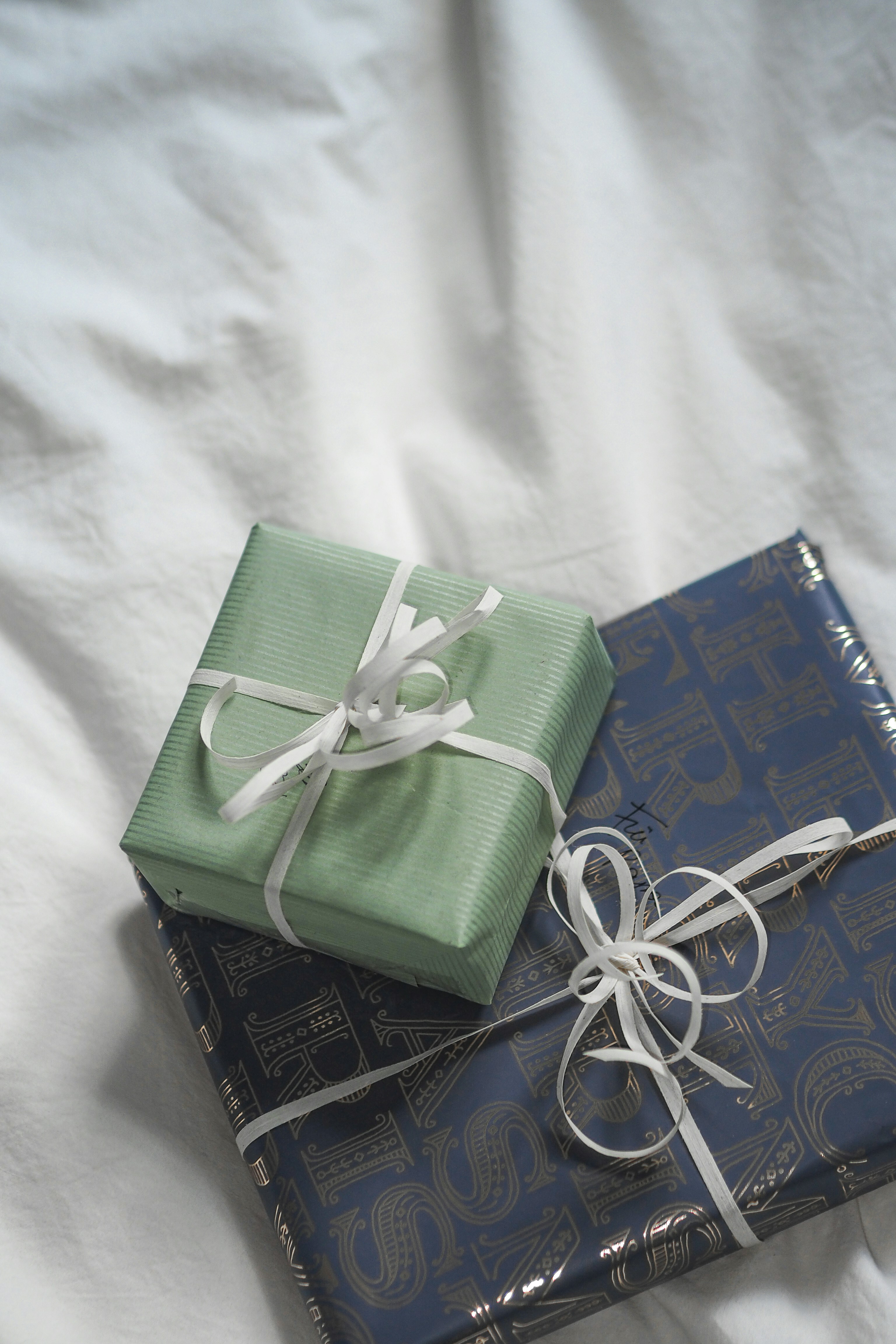 Two wrapped presents sitting on top of a bed