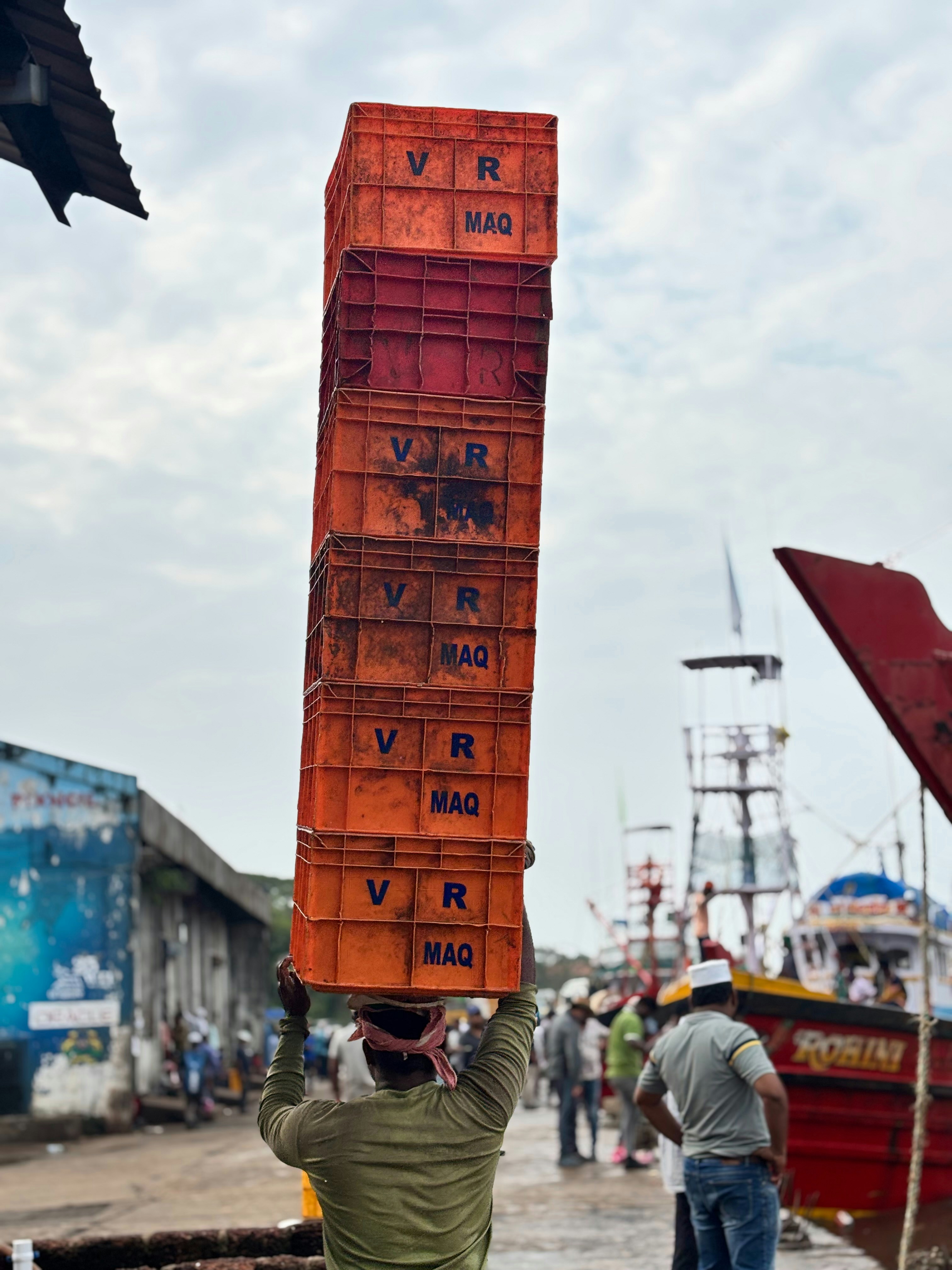 A man holding a large stack of orange crates