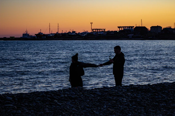 A couple of people standing on top of a beach