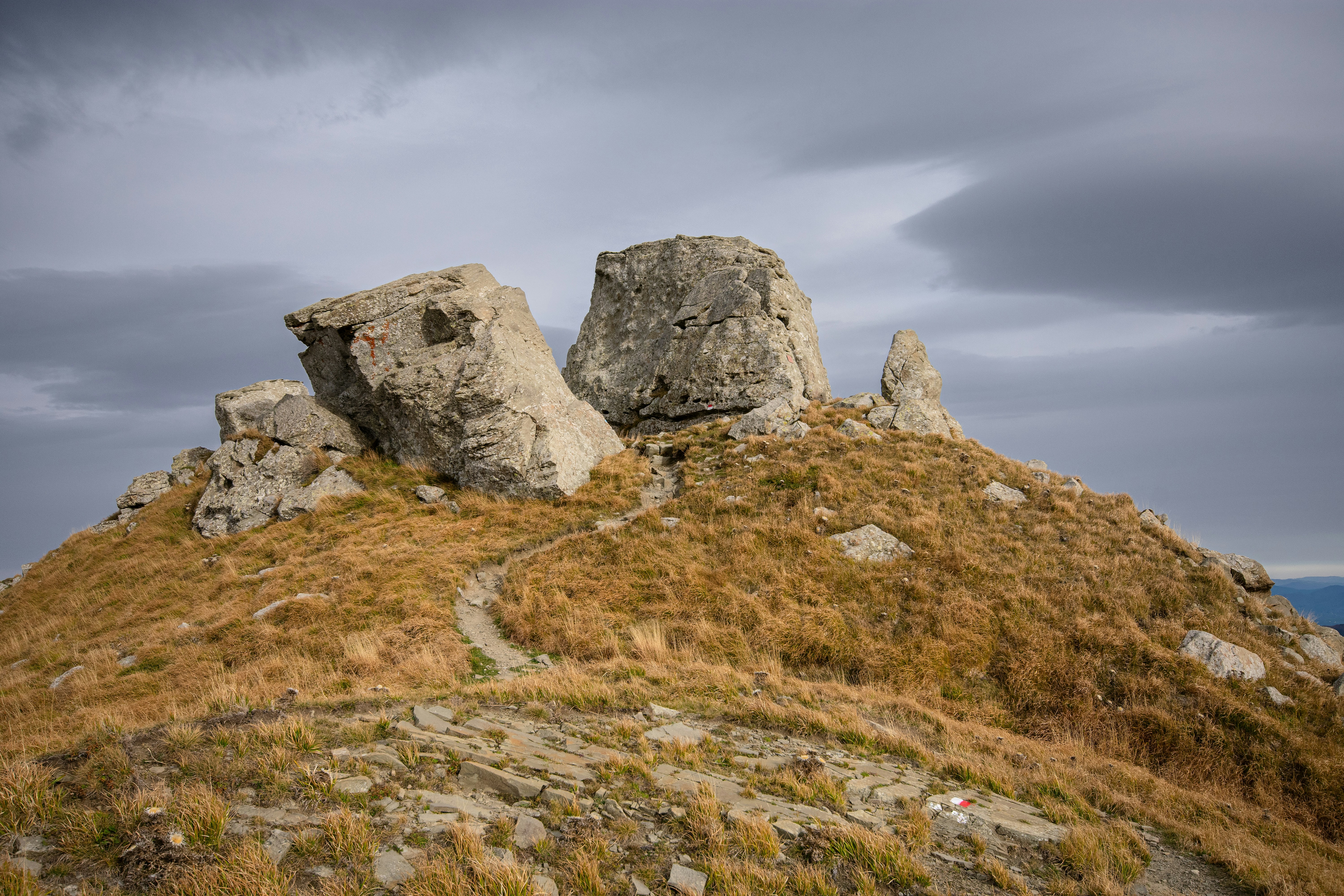 A rock formation on top of a grassy hill
