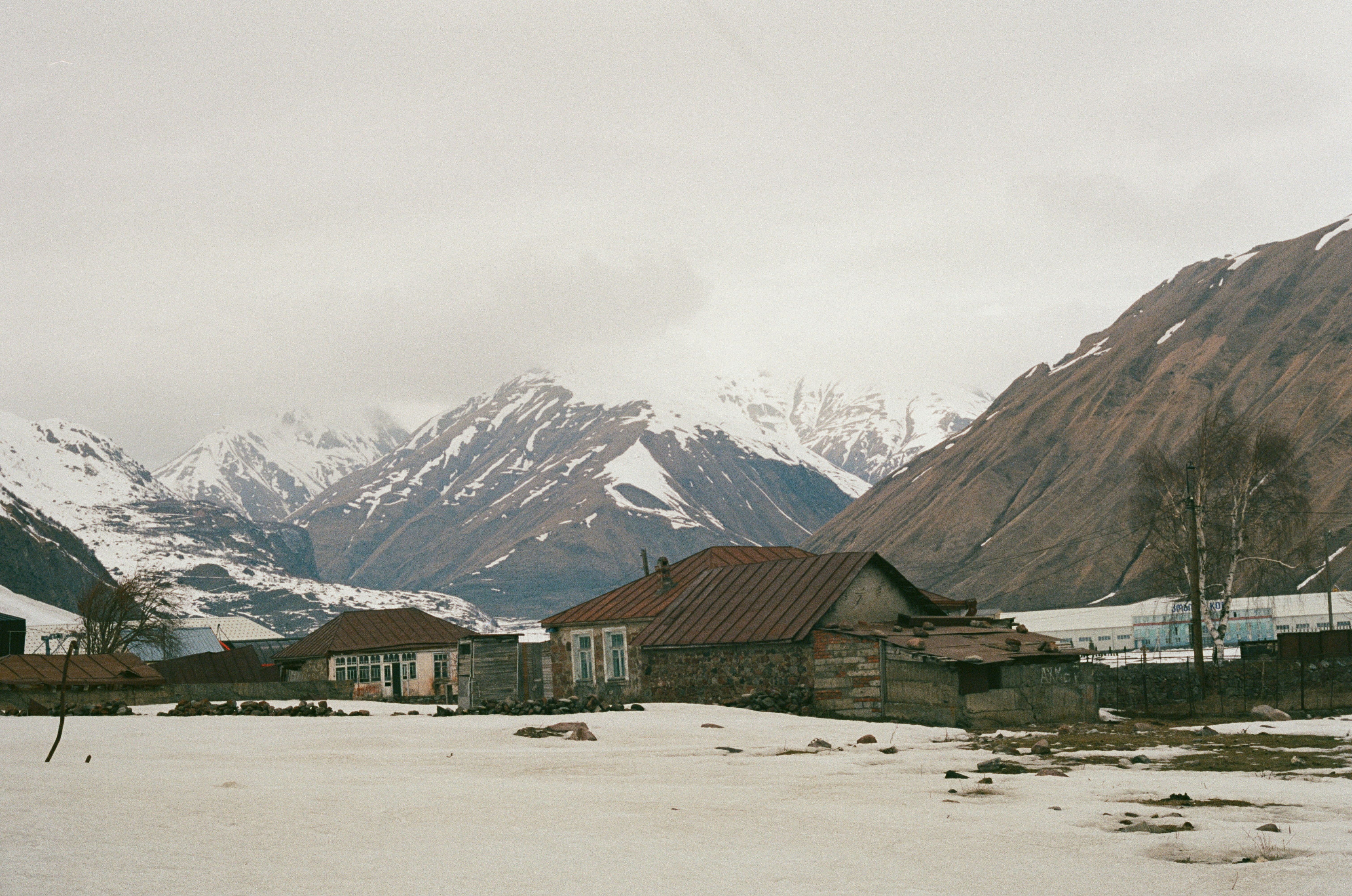 A snow covered field with houses and mountains in the background