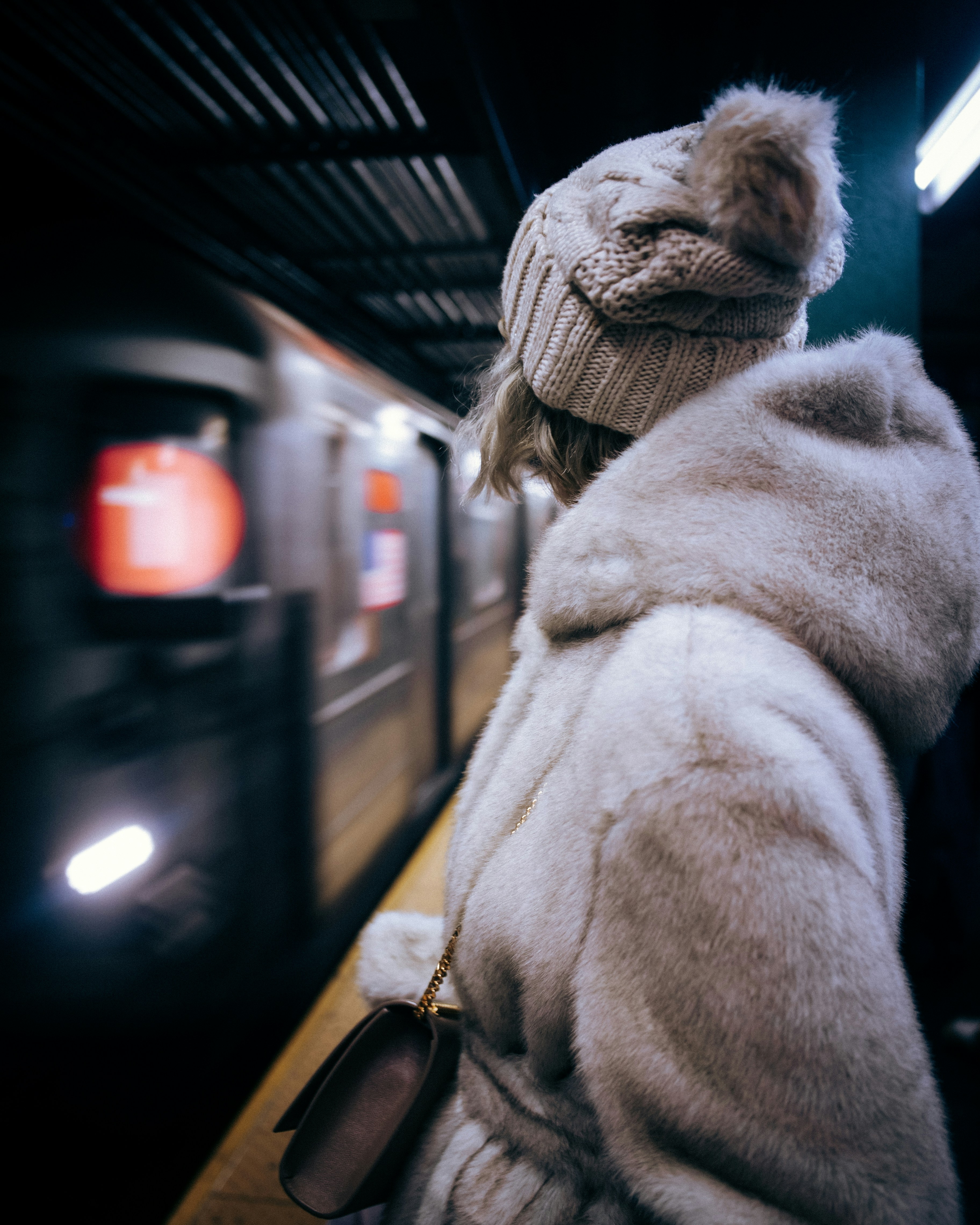 A woman in a fur coat waiting for a train