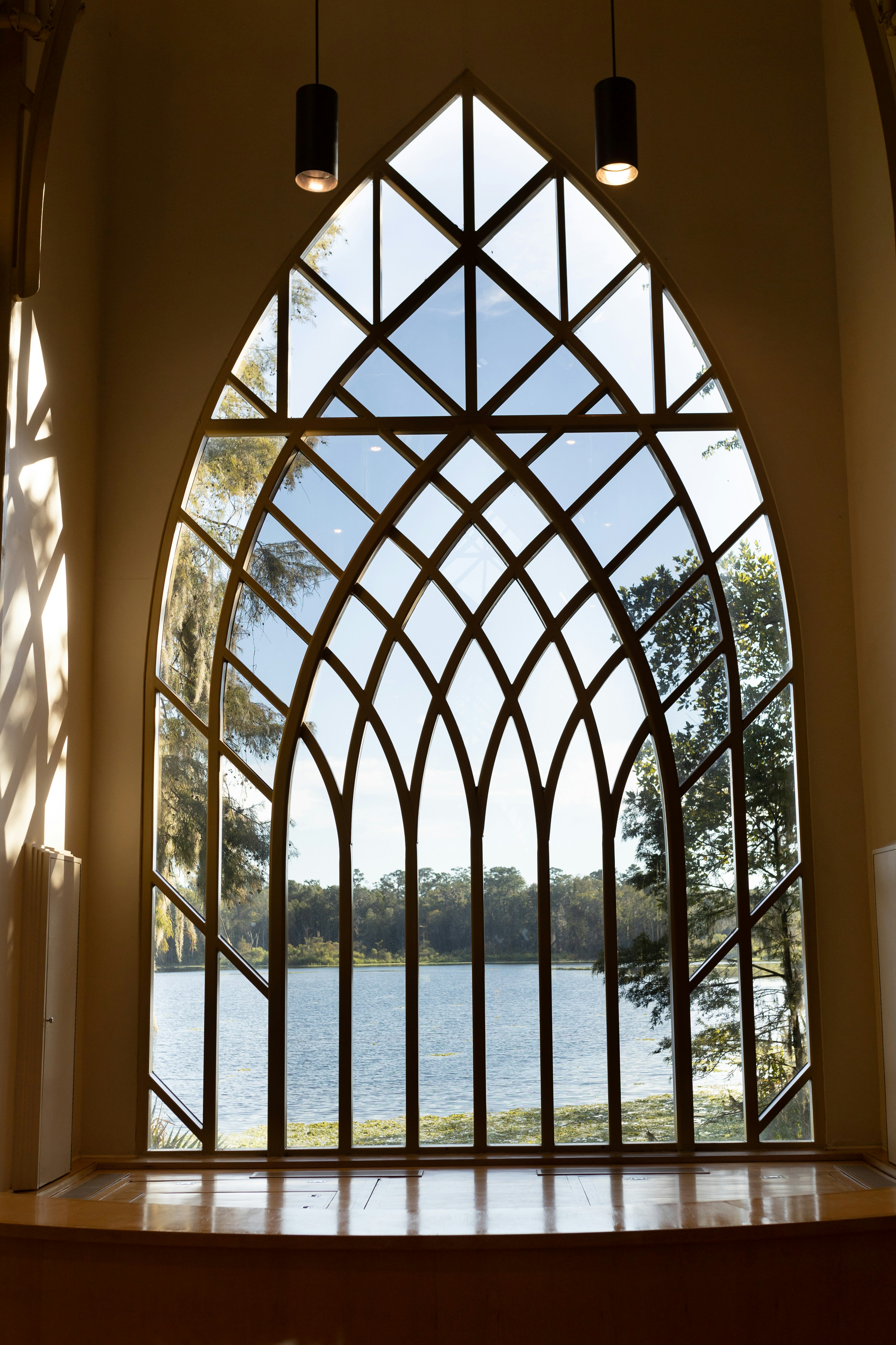 A large arched window with a view of a lake