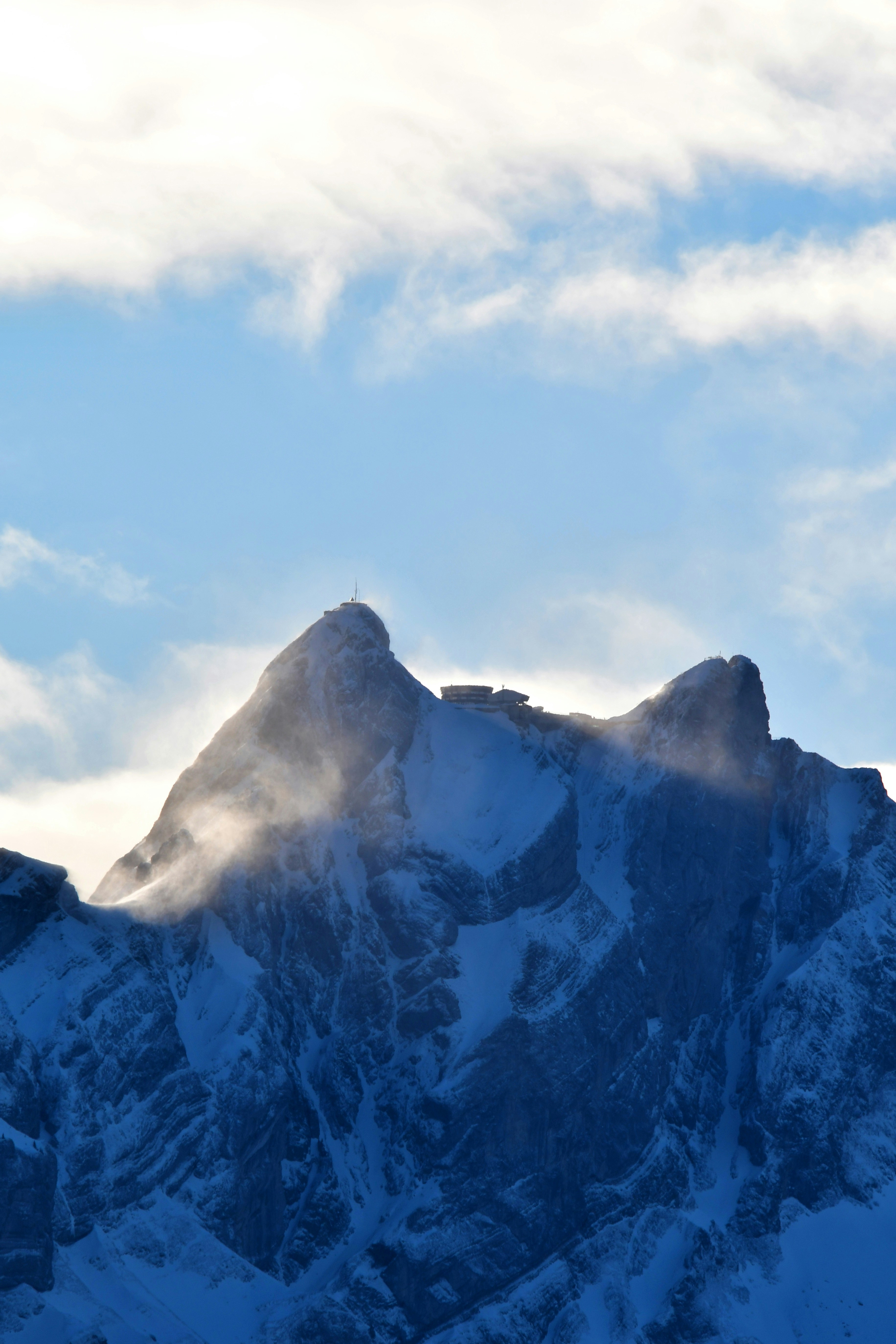A snow covered mountain with clouds in the sky