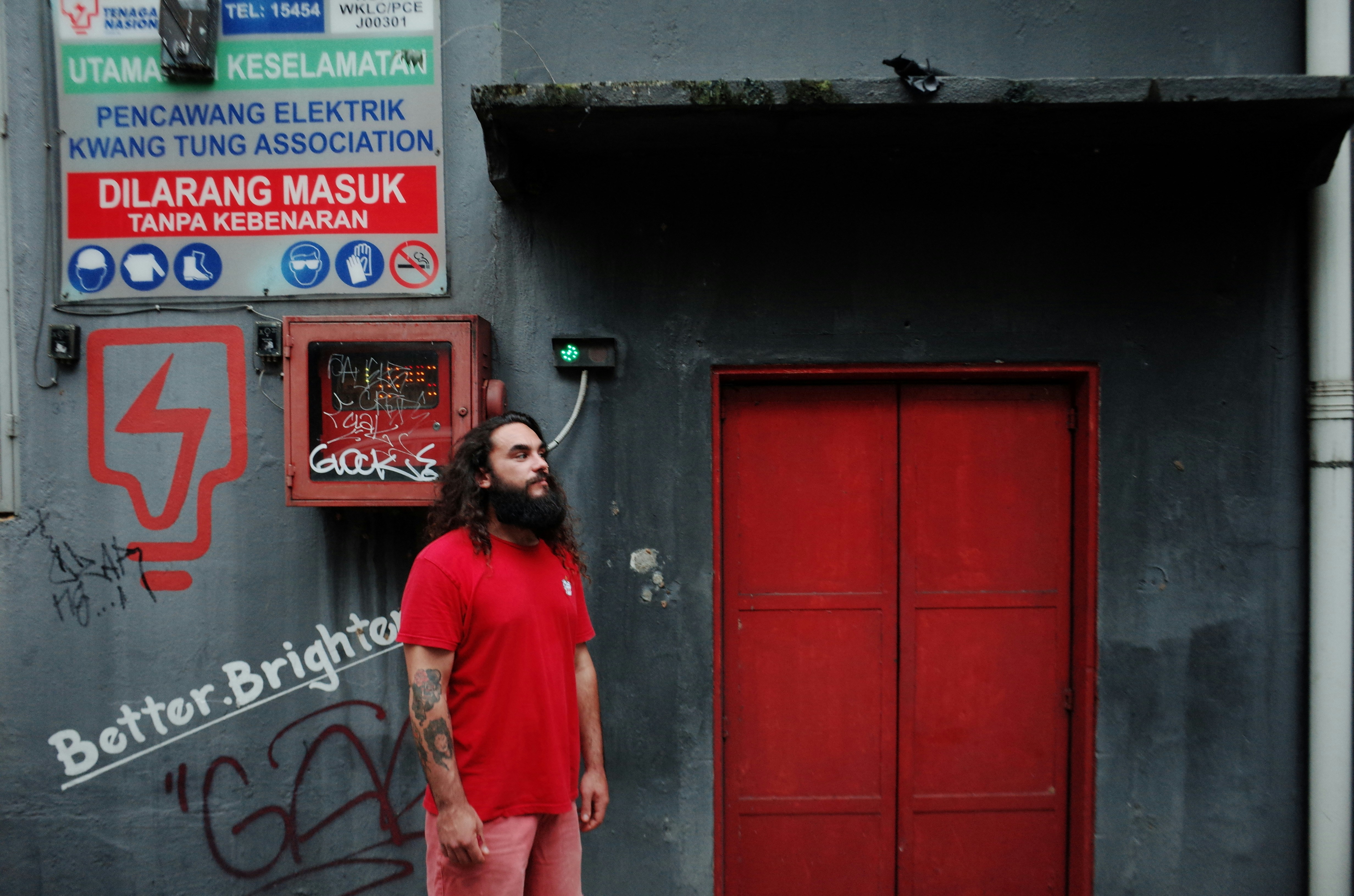 Seorang pria berdiri di depan pintu merah
