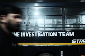 A blurry photo of a man walking in front of a bus