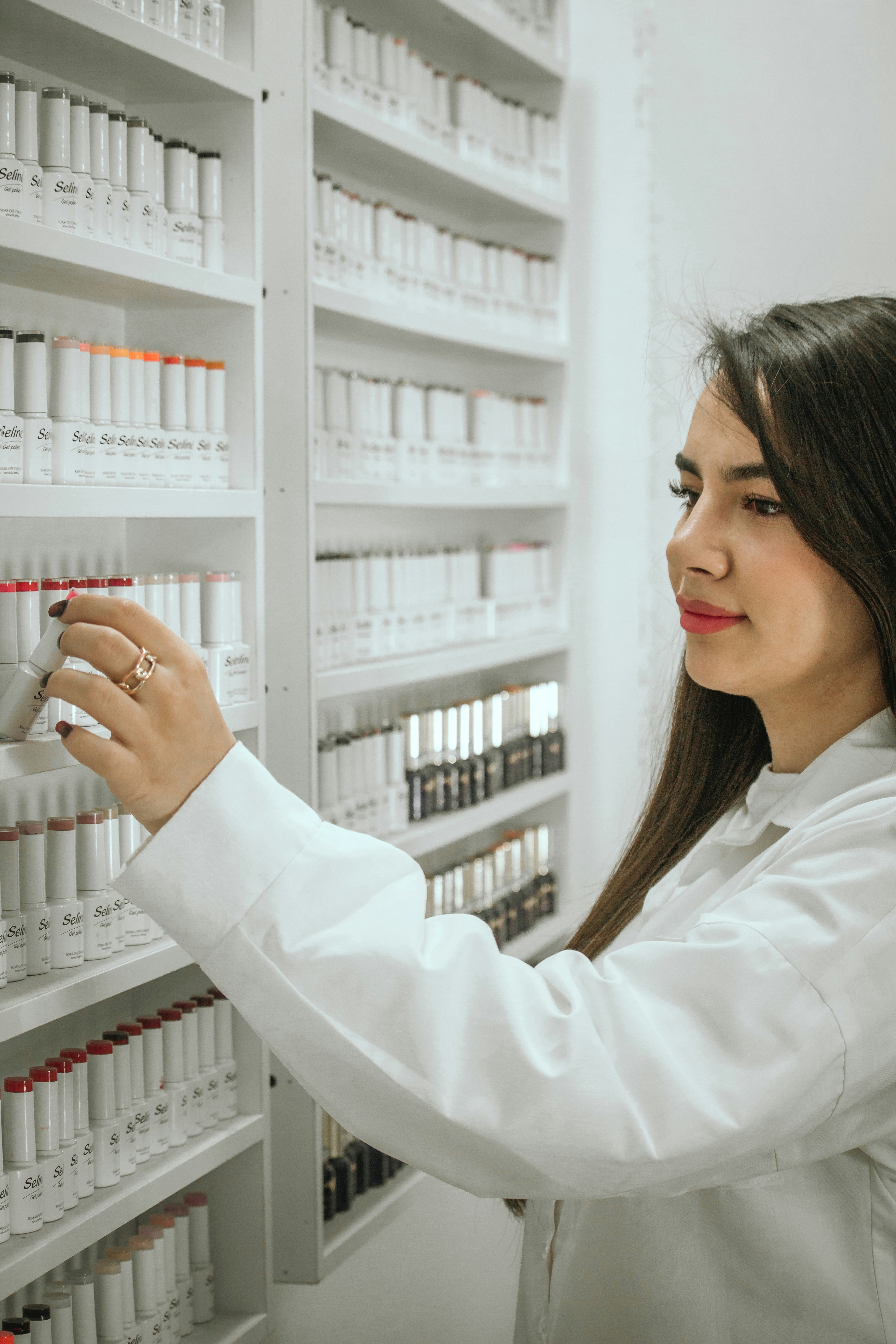 A woman in a white lab coat working on a shelf