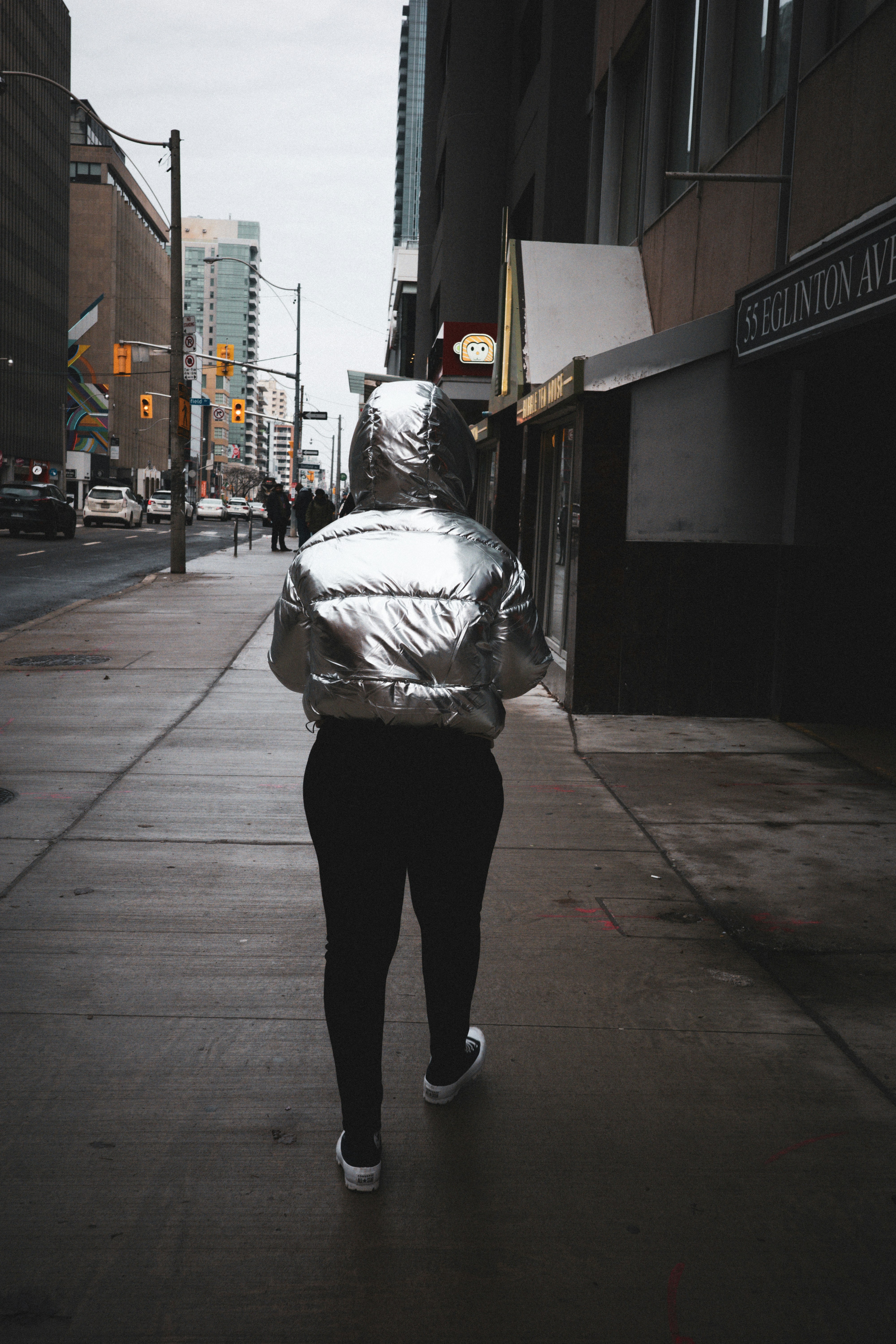 A woman walking down a sidewalk in a shiny jacket