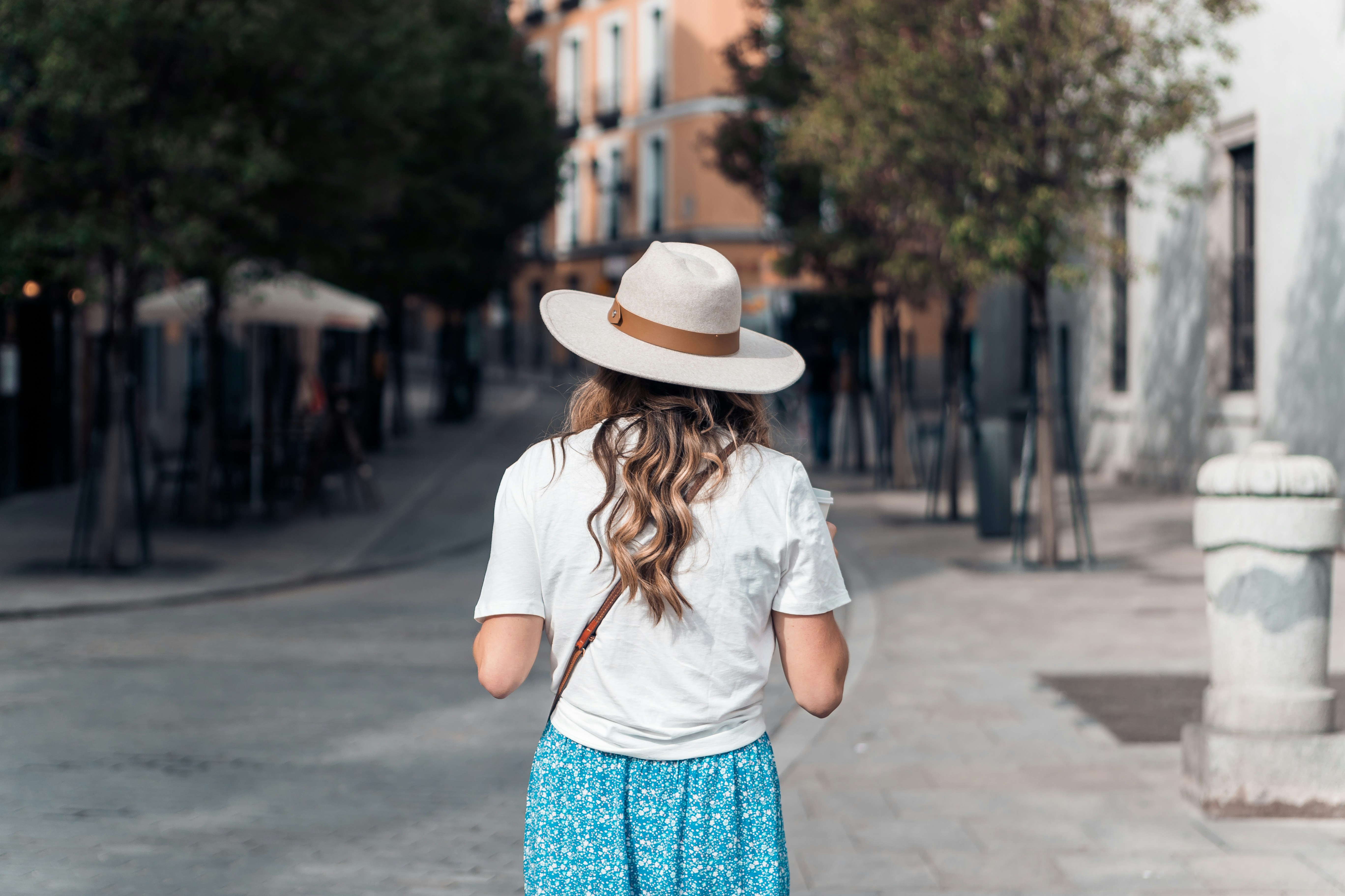 A woman in a hat is walking down the street