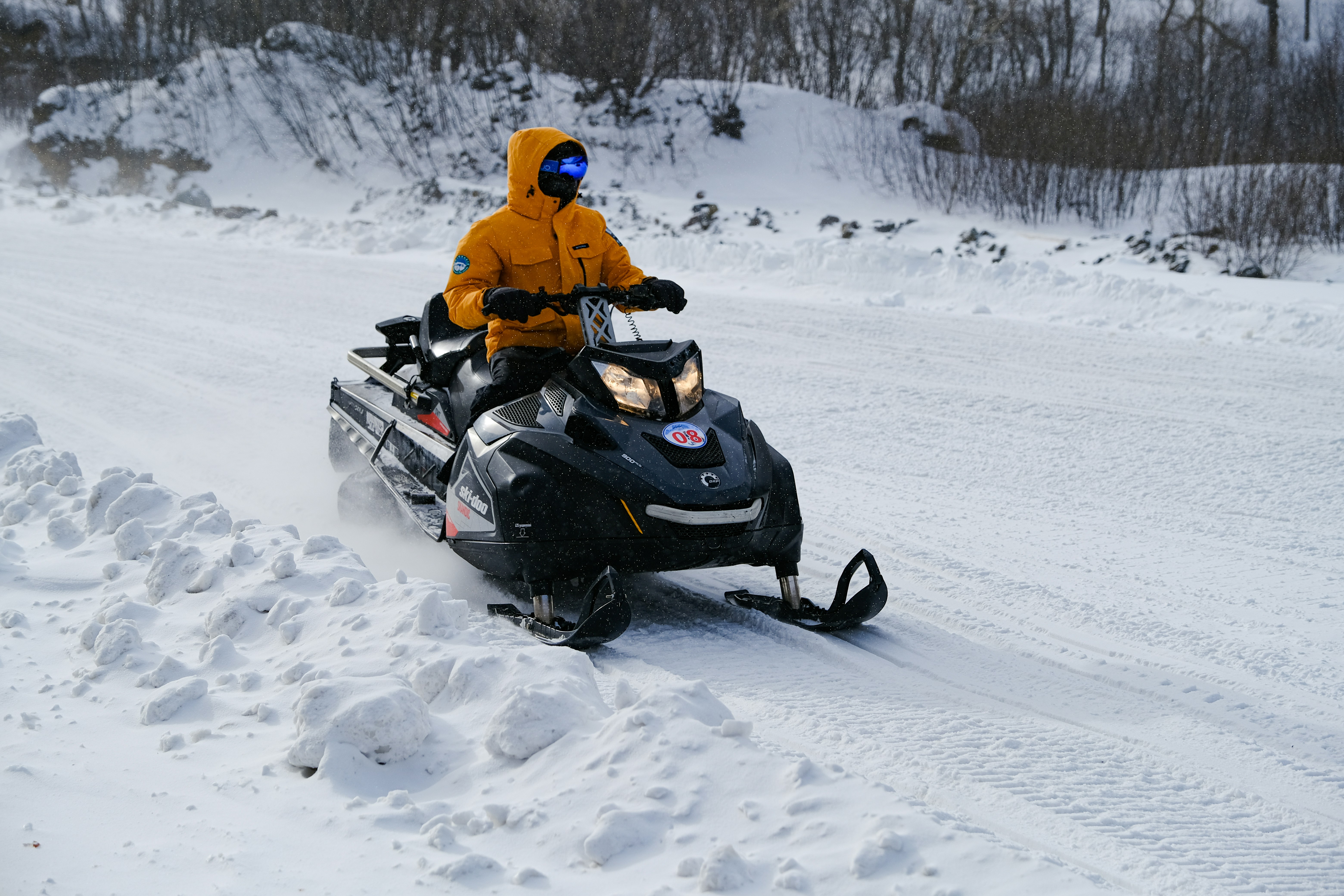 Un hombre montando una moto de nieve por una carretera cubierta de nieve