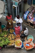 A group of people standing around a table filled with fruits and vegetables