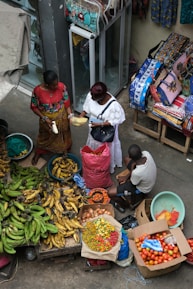 A group of people standing around a table filled with fruits and vegetables