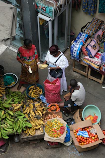 A group of people standing around a table filled with fruits and vegetables