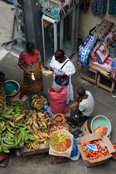 A group of people standing around a table filled with fruits and vegetables