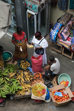 A group of people standing around a table filled with fruits and vegetables