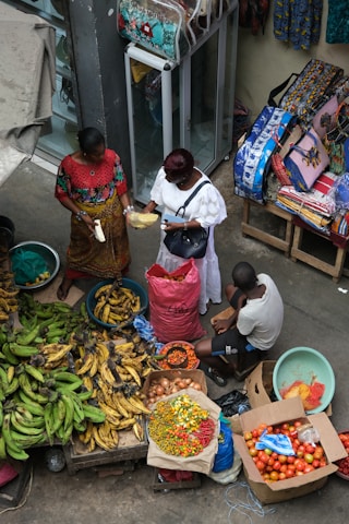 A group of people standing around a table filled with fruits and vegetables