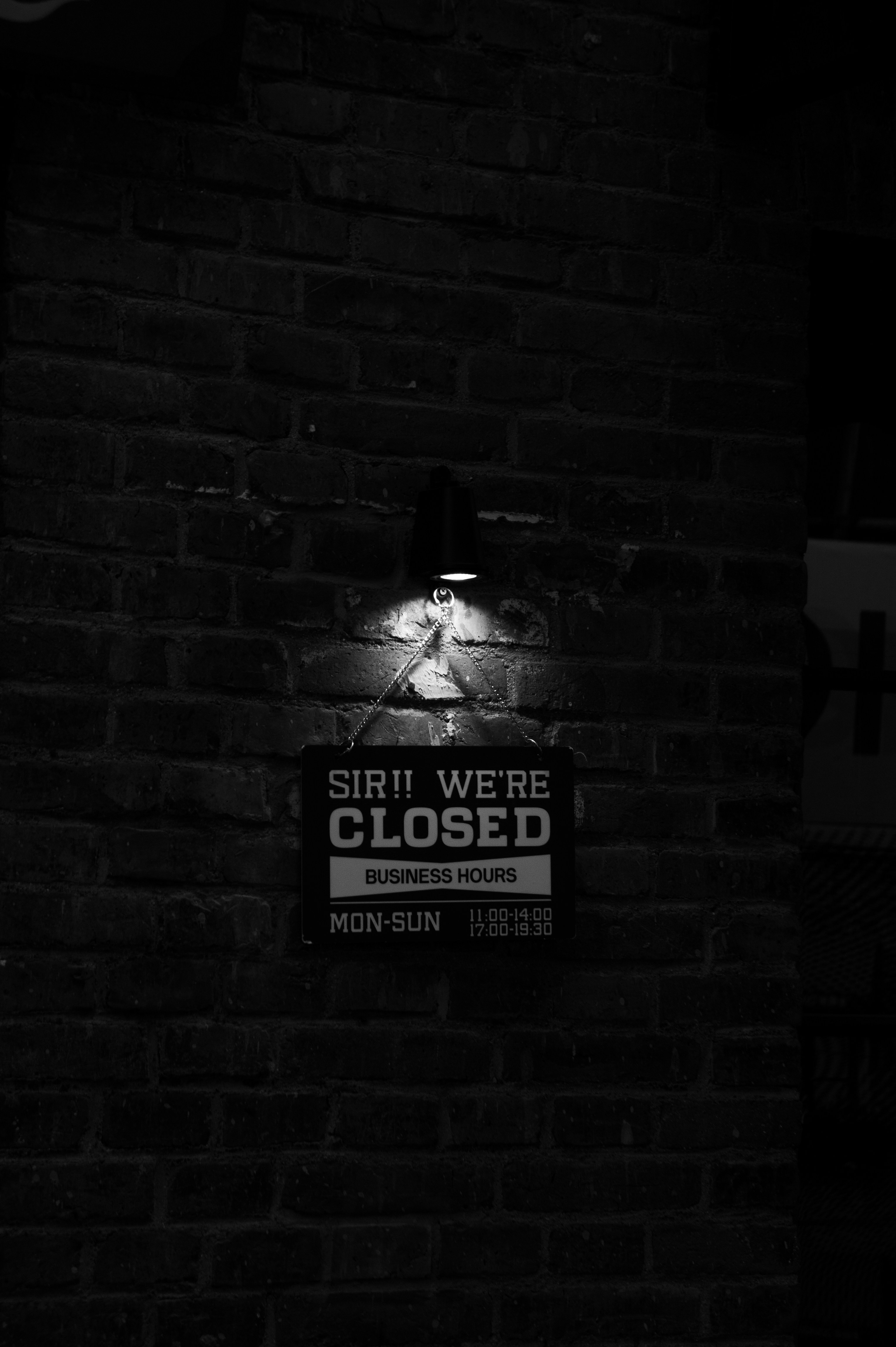 A black and white photo of a sign on a brick wall