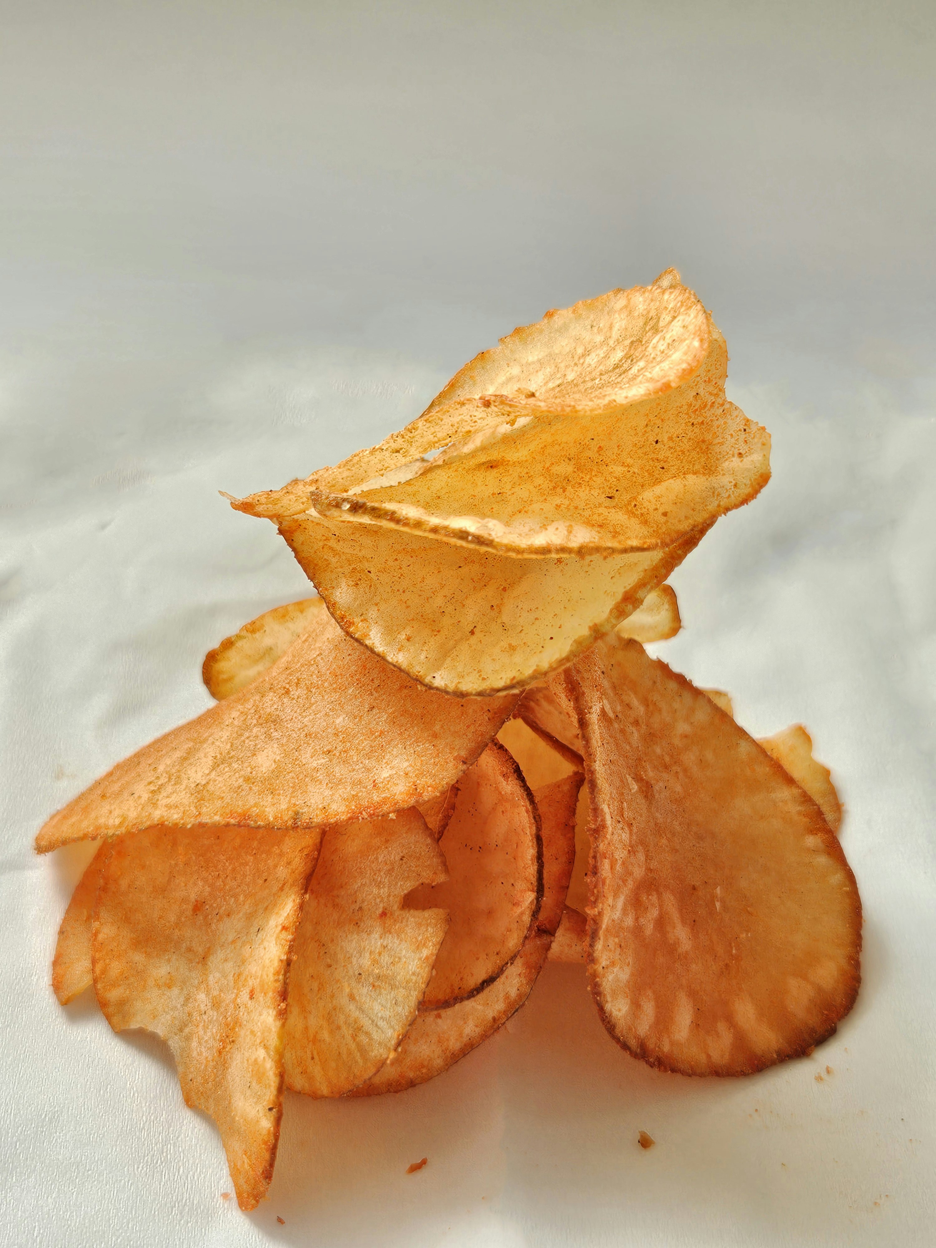 Crispy potato chips in bowl on clean white surface