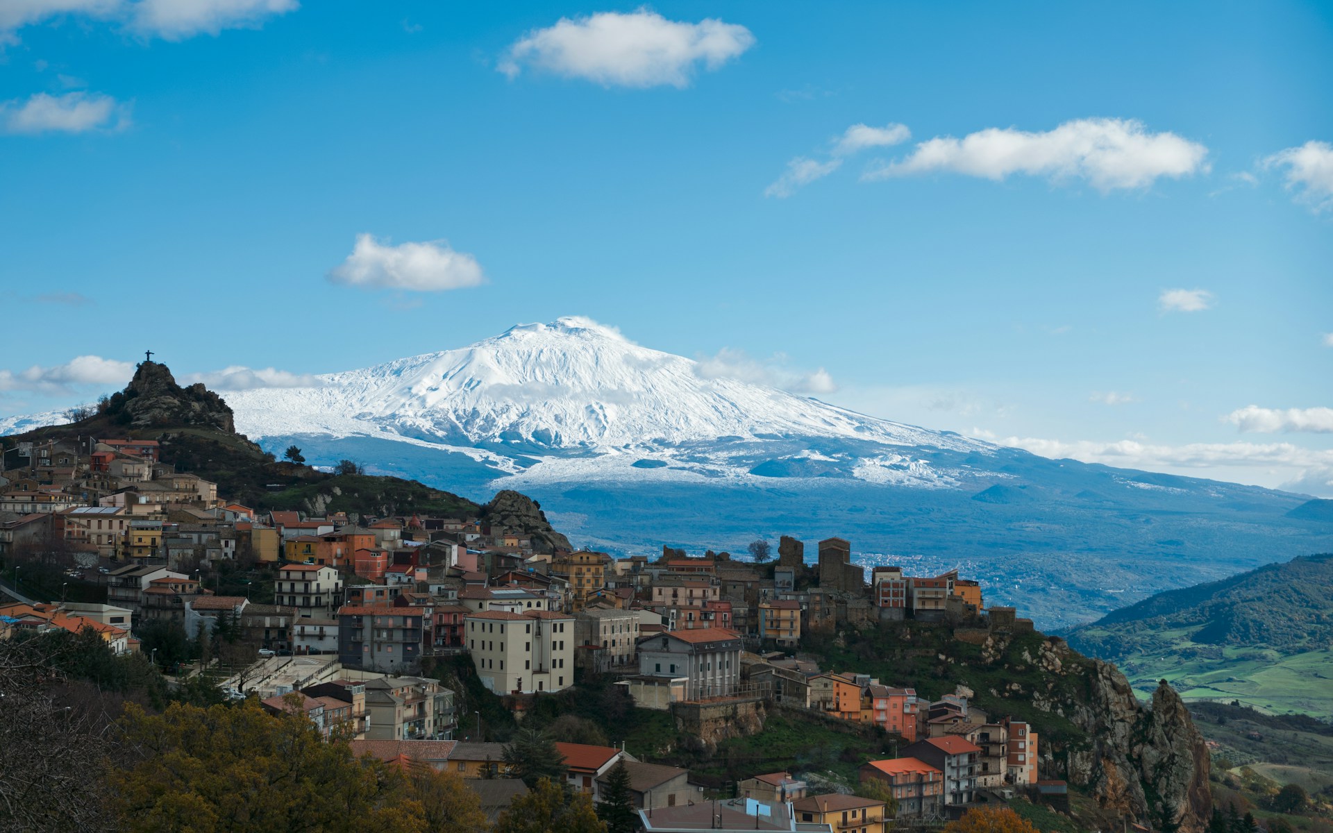 A small village on a hill with a snow capped mountain in the background