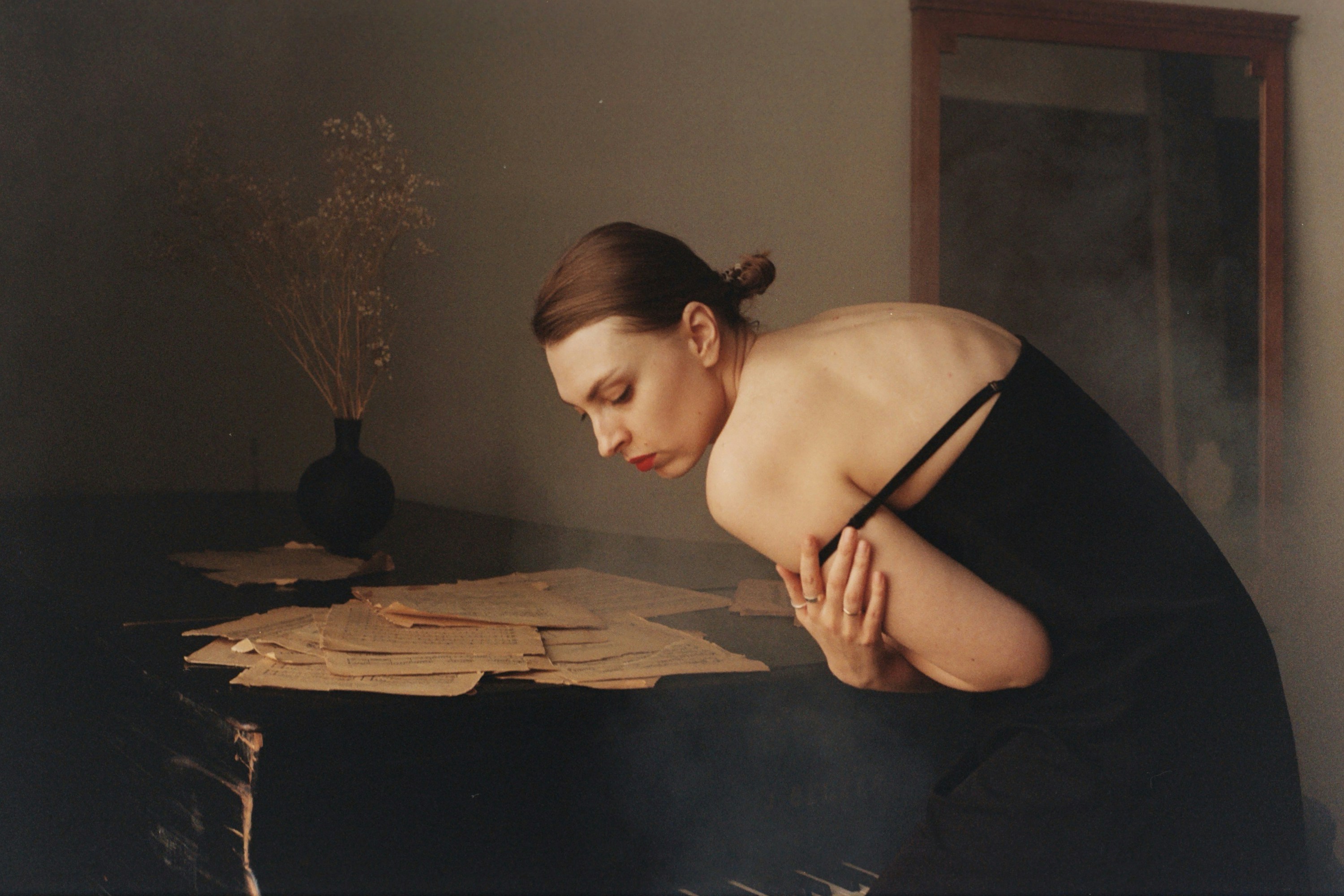 A woman in a black dress leaning over a table