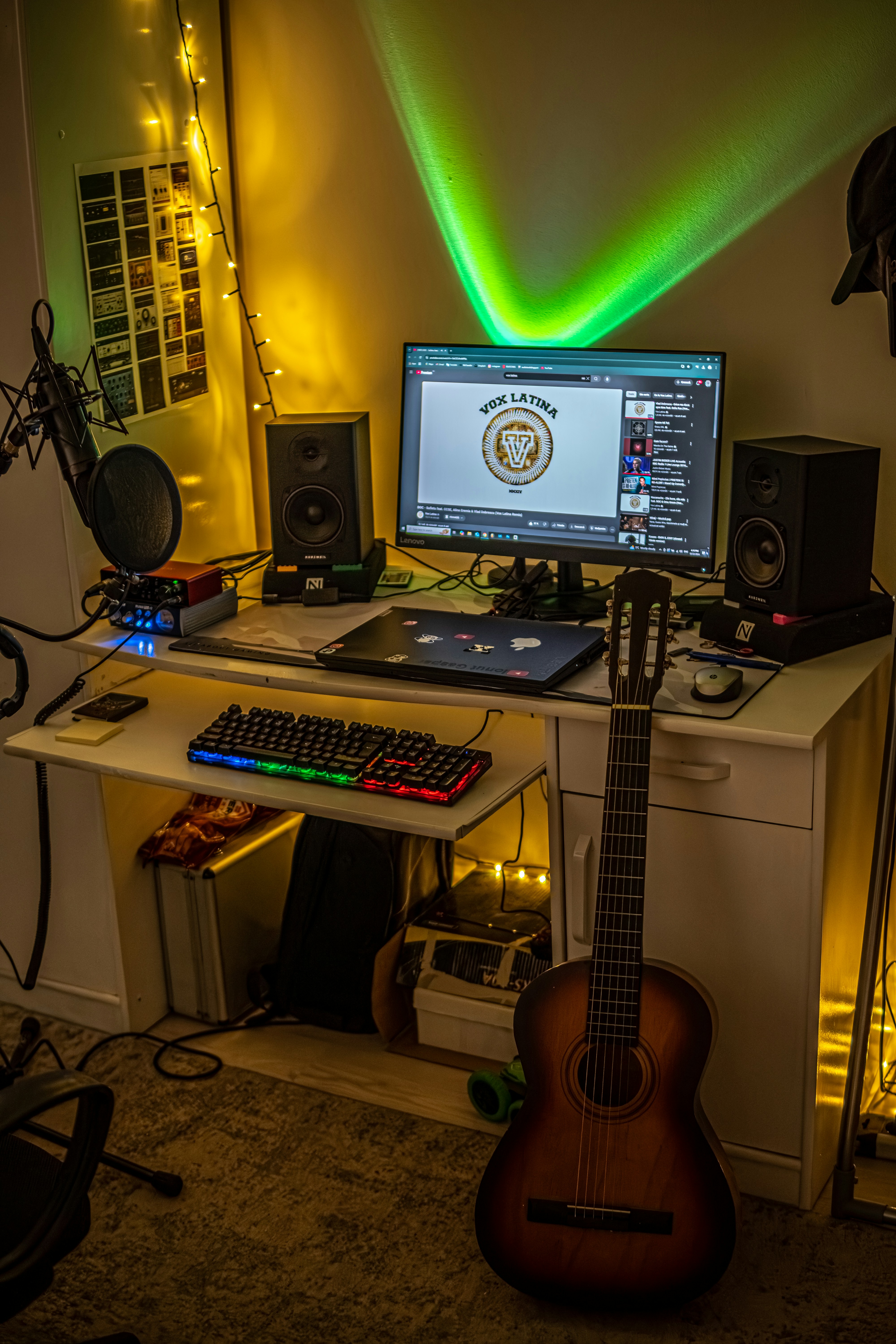 A desk with a guitar and a computer on it