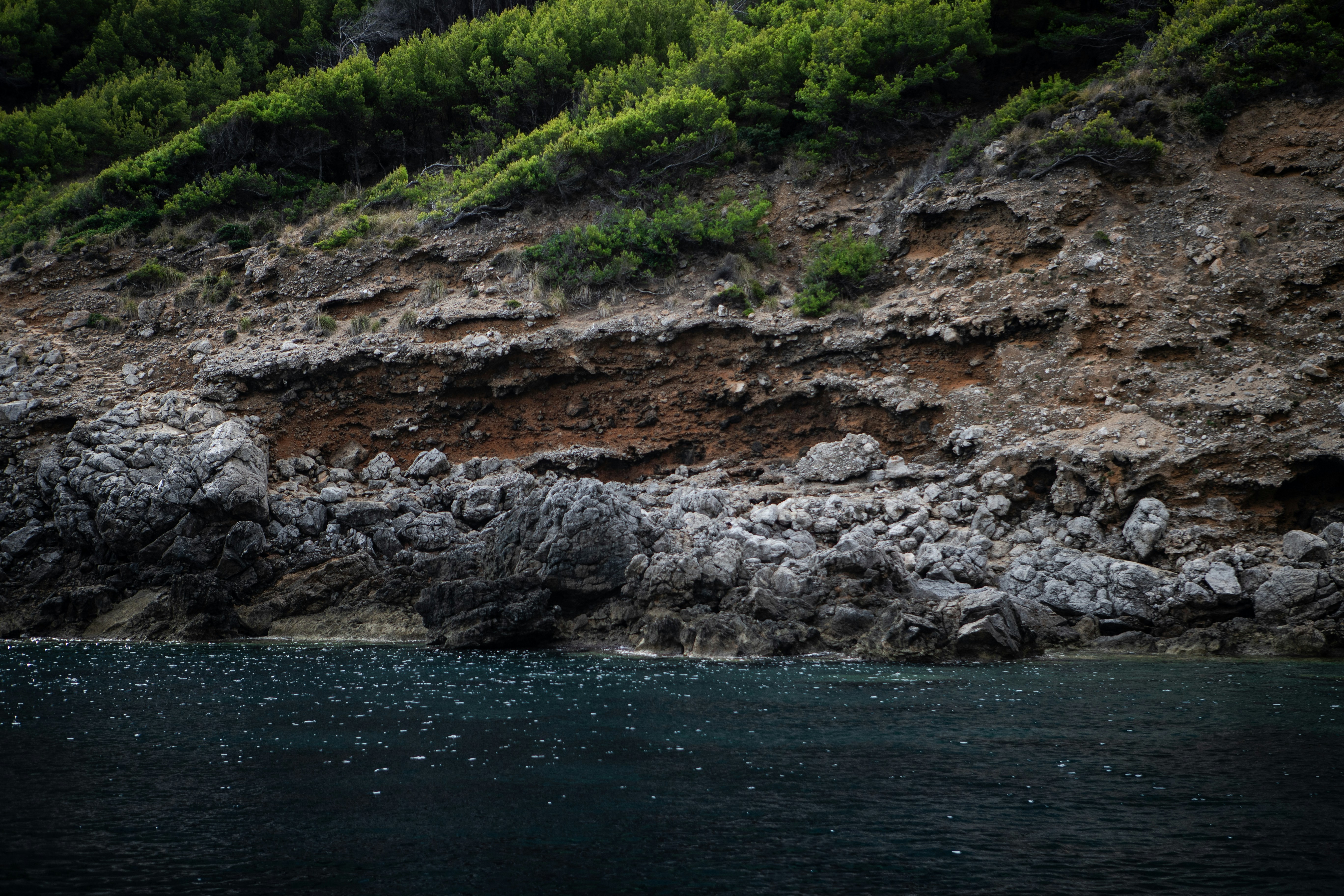 A large body of water sitting below a lush green hillside